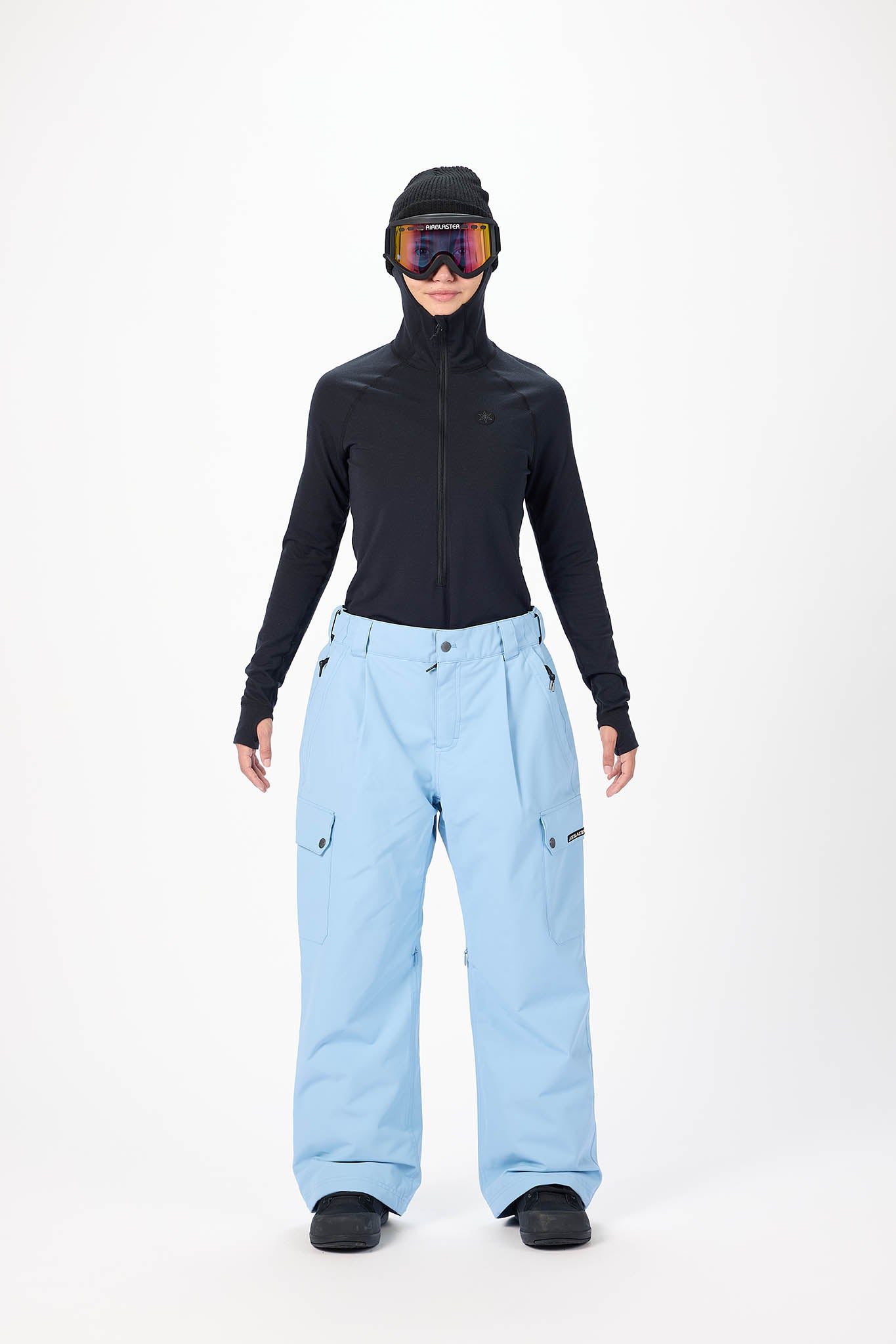 Person wearing a black jacket and light blue pants with ski goggles on a white background