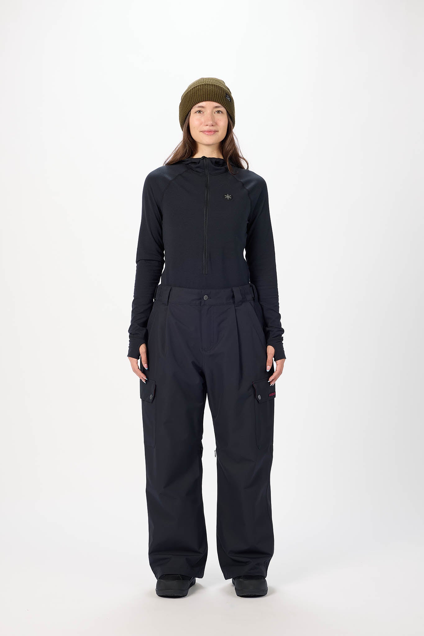 Person wearing a black snowsuit and green beanie on a white background