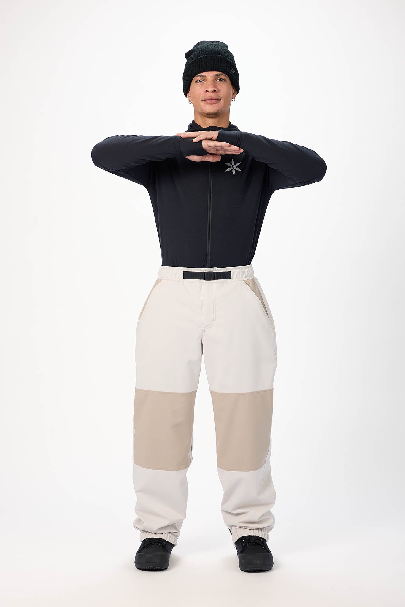 Person wearing a black top and beige pants on a white background