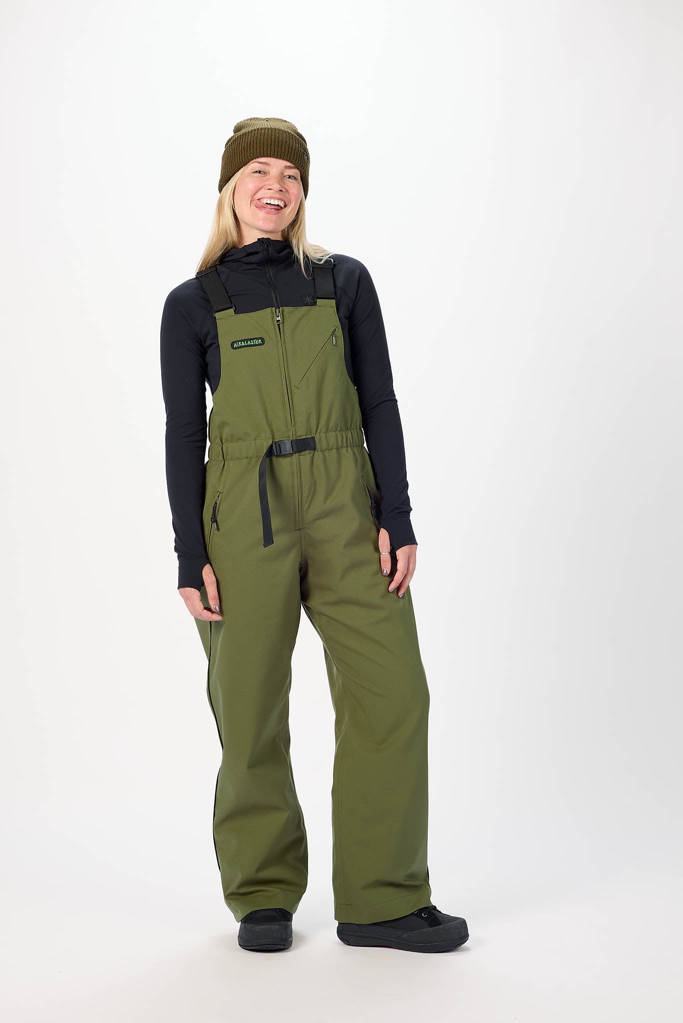 Person wearing green bib overalls and a black jacket on a white background