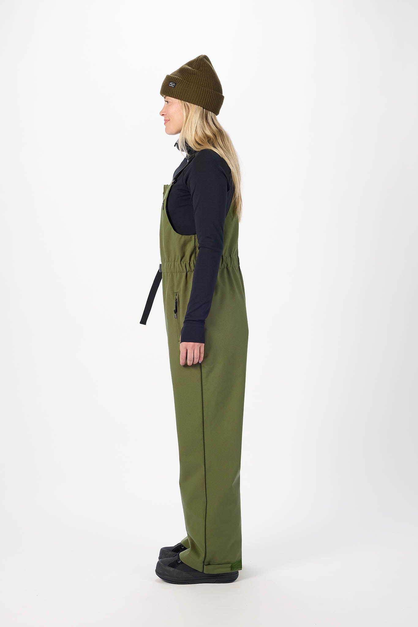 Person wearing green overalls and a brown beanie on a white background