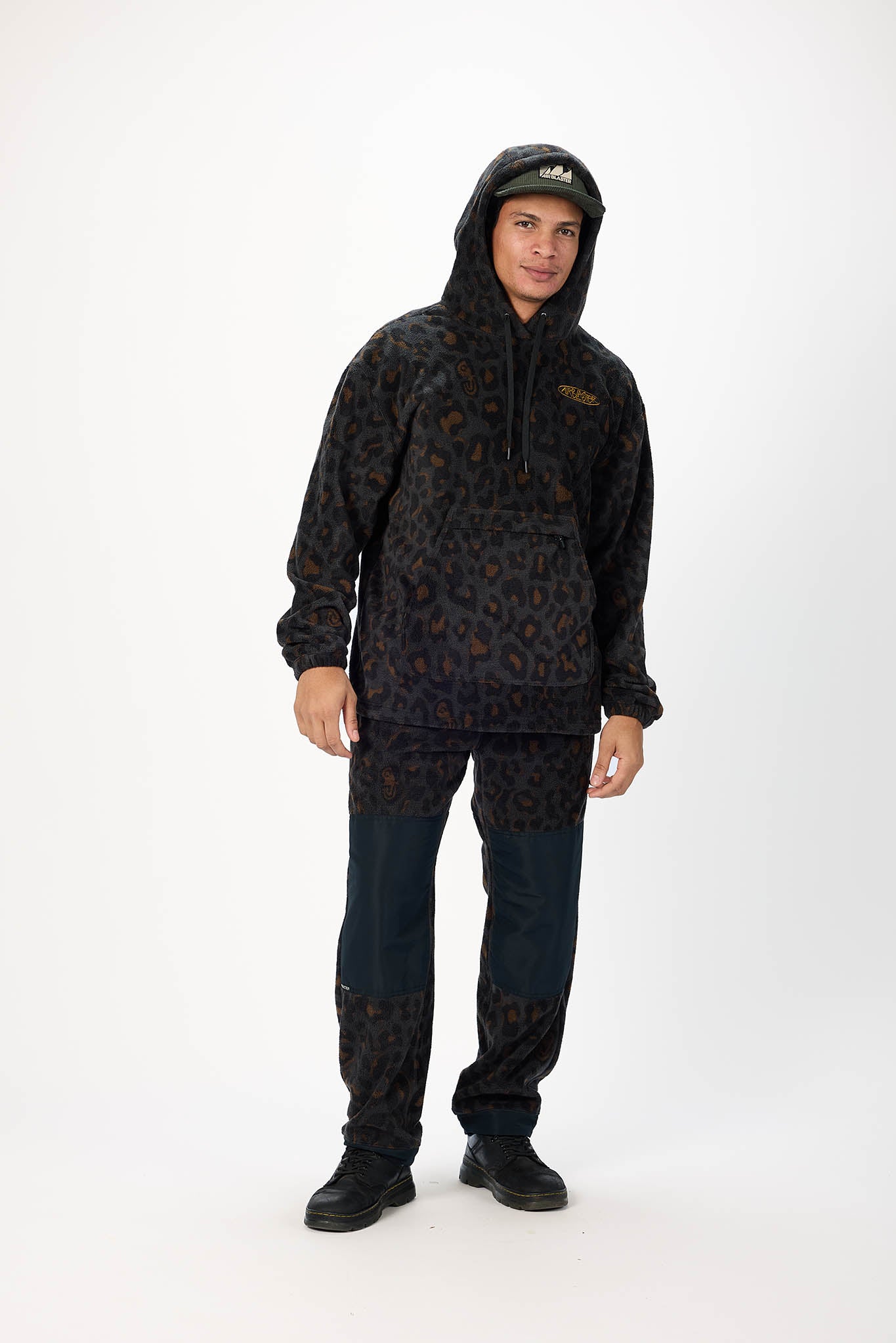 A man modeling a black and brown leopard-print fleece hoodie and matching pants against a plain white studio background.