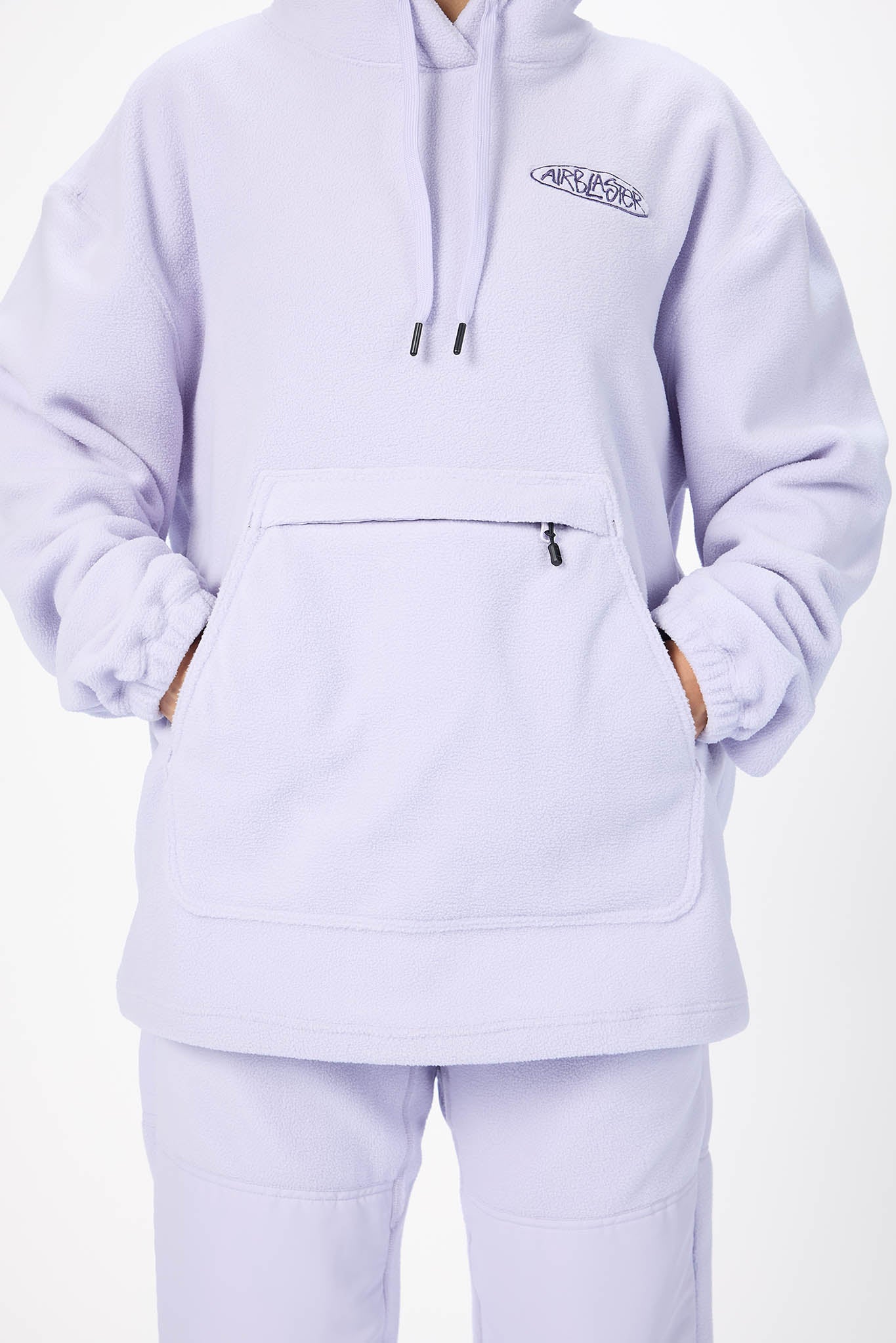 A person wearing a light lavender pullover hoodie with a kangaroo pocket and matching sweatpants against a plain white background.