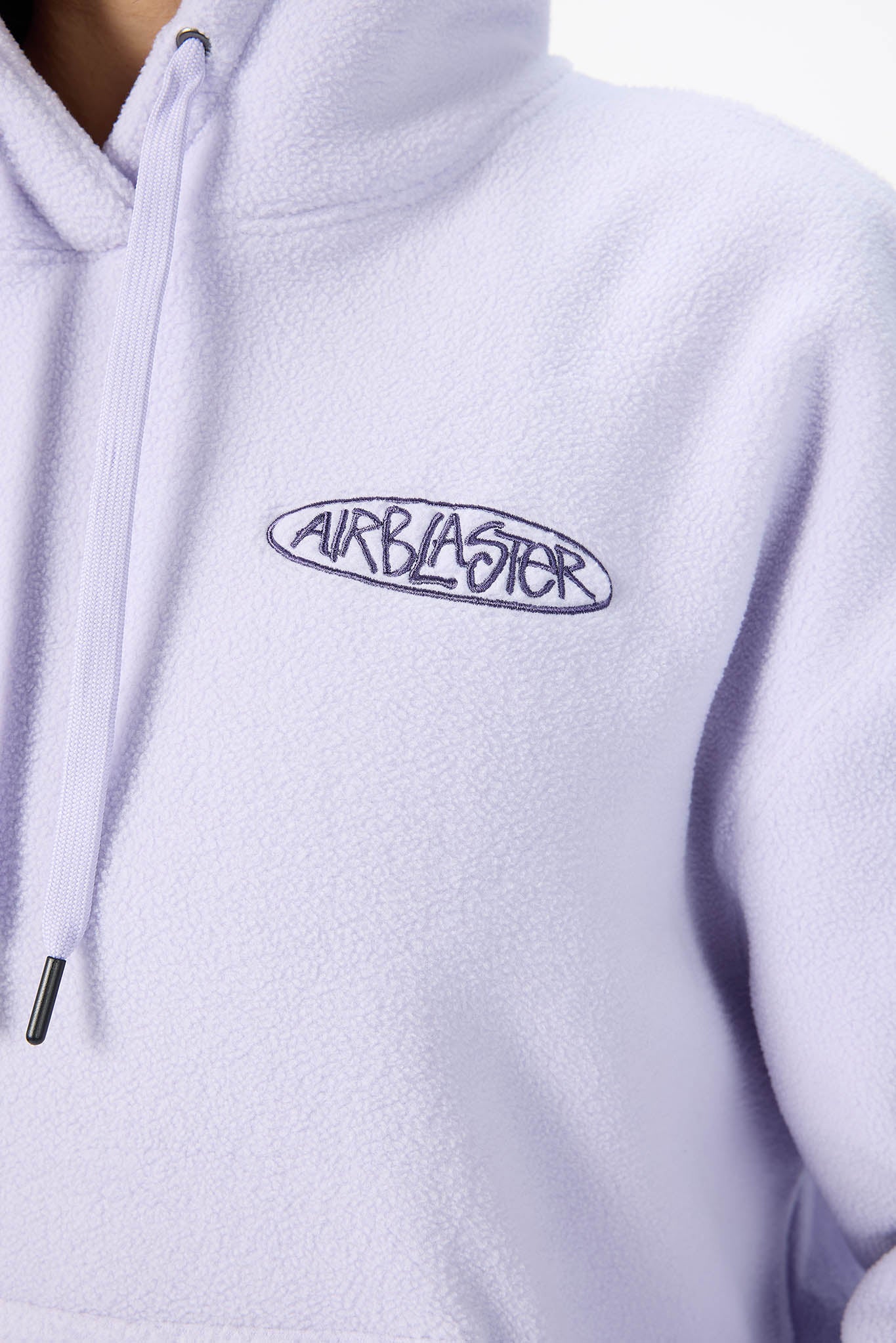 Close-up of a light lavender fleece pullover hoodie with a dark navy embroidered 'AIRBLASTER' logo on the chest.