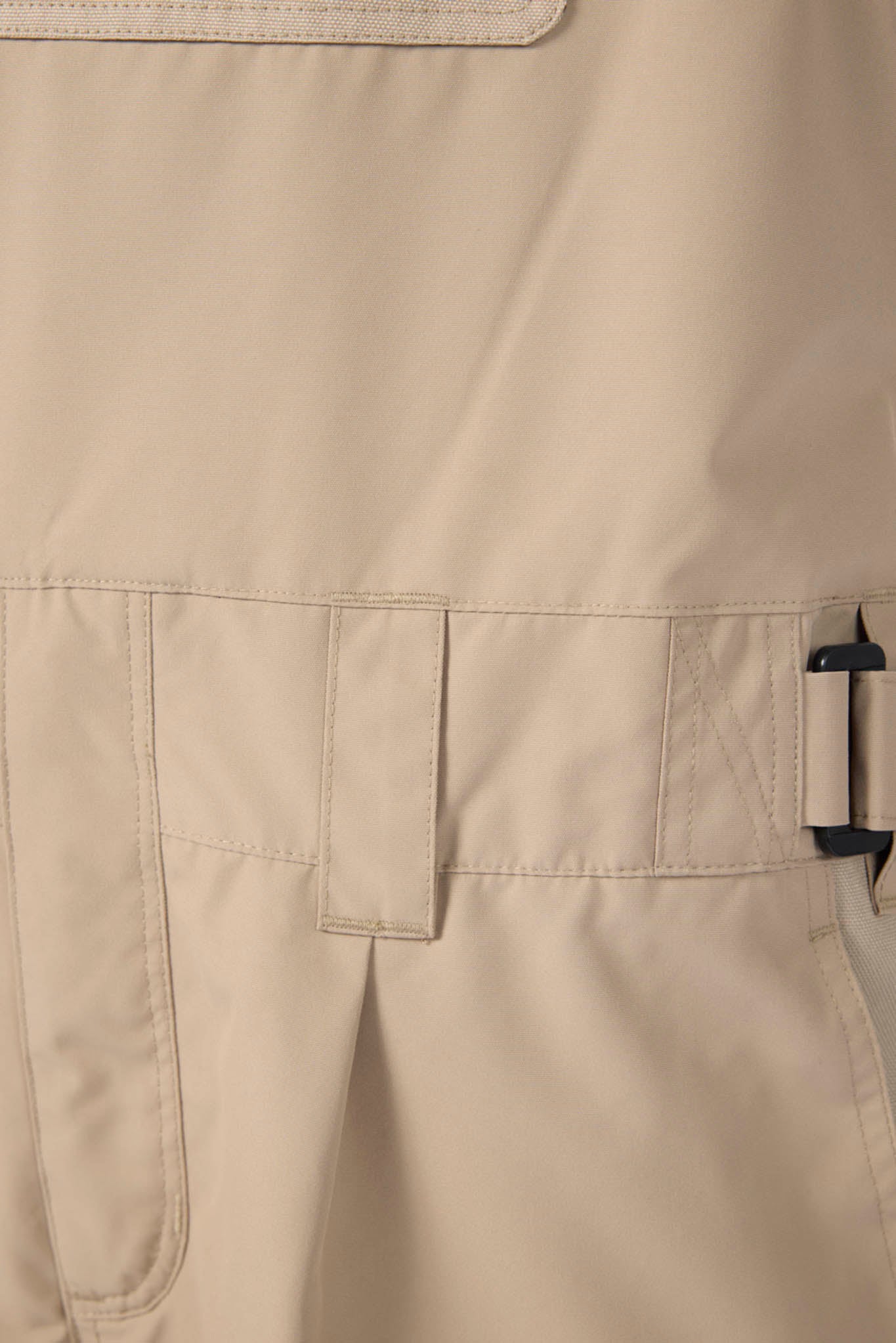Close-up of beige pants with a buckle detail