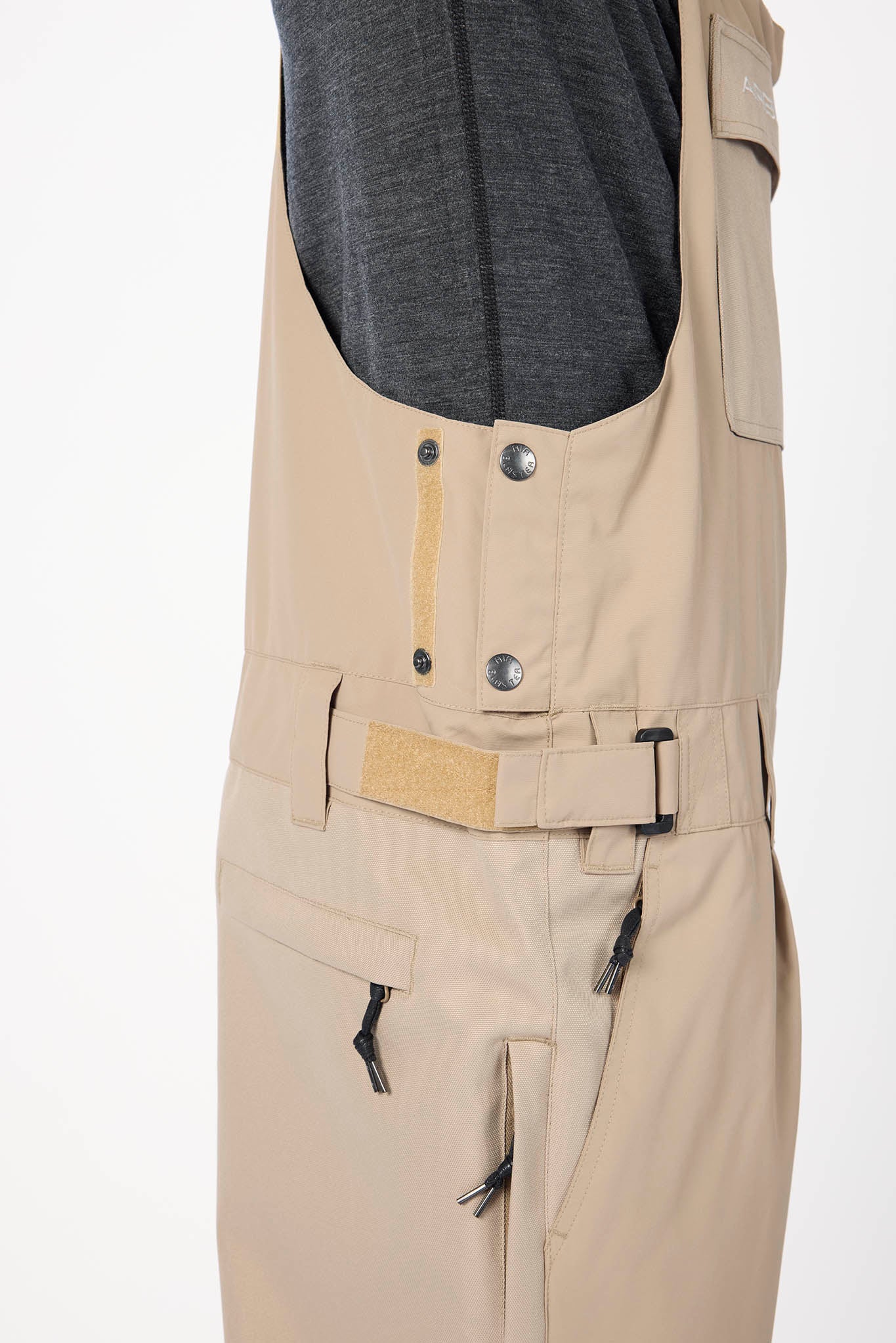 Beige pants with multiple pockets and buttons on a white background