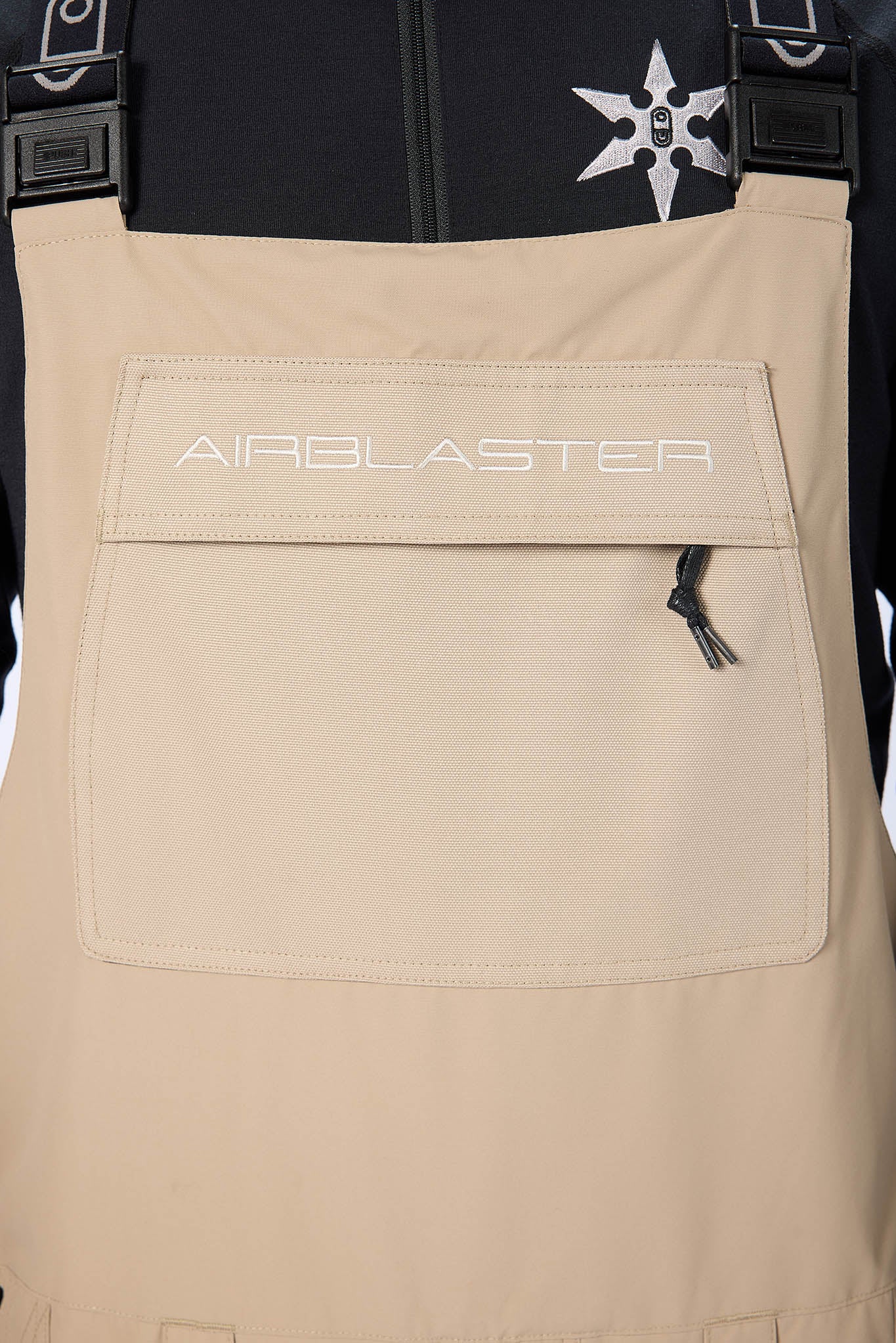 Beige bib overalls with 'Airblaster' branding on a white background