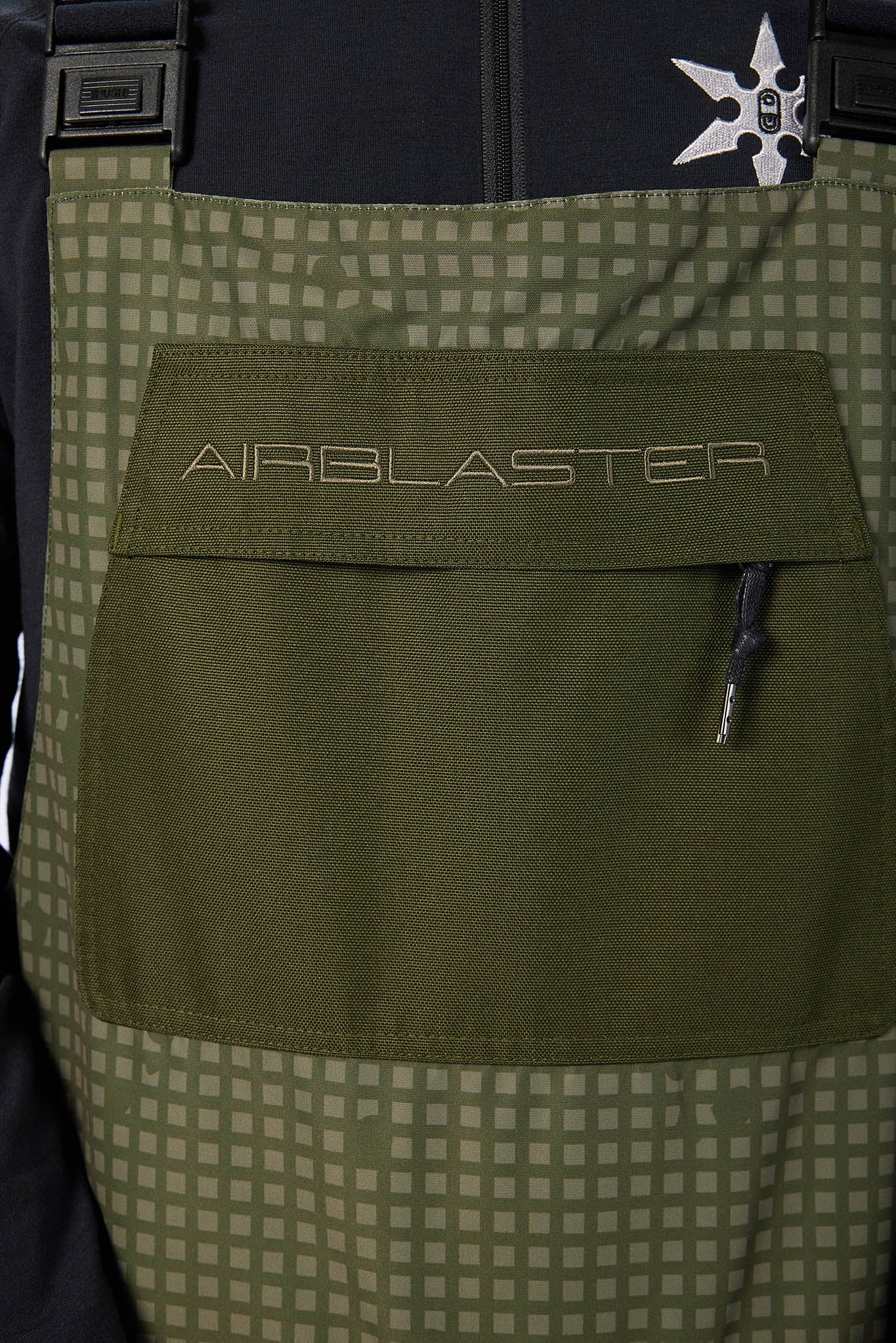 Green Airblaster bib overalls with a checkered pattern on the background