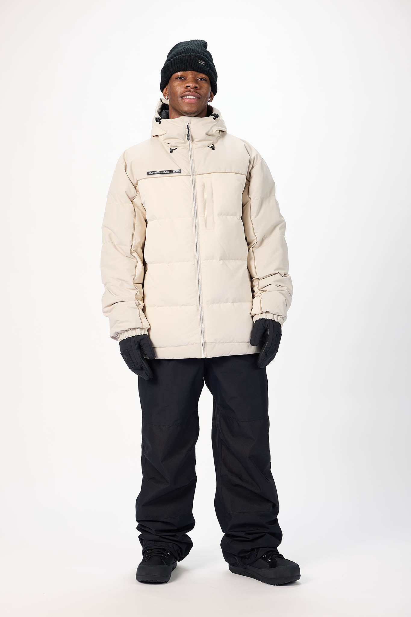 Person wearing a beige winter jacket and black pants on a white background