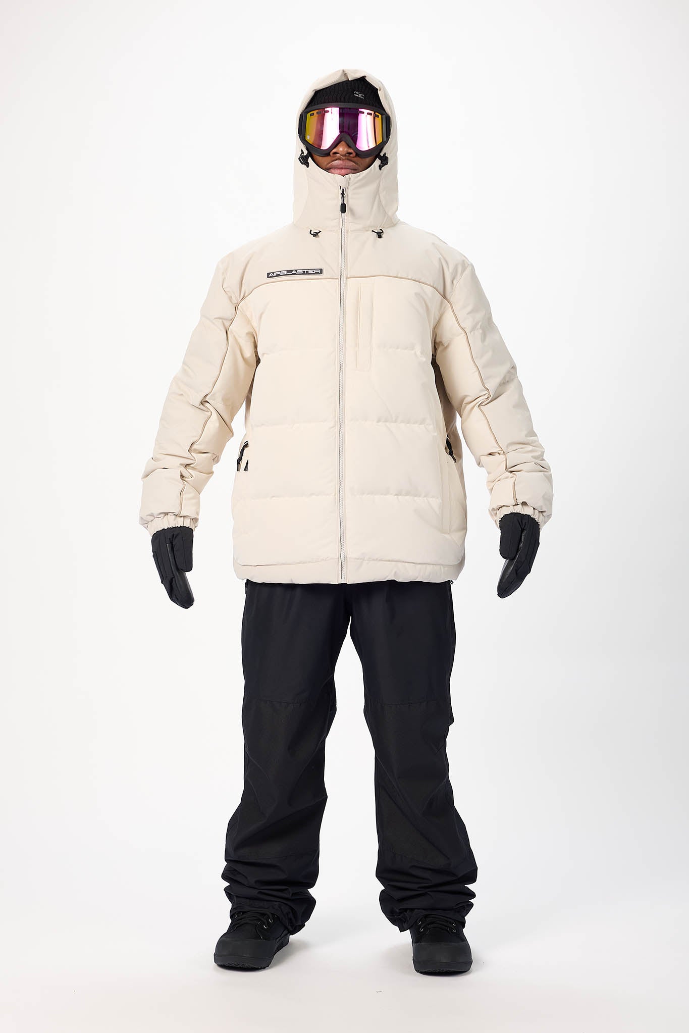 Person wearing a beige winter jacket and black pants on a white background