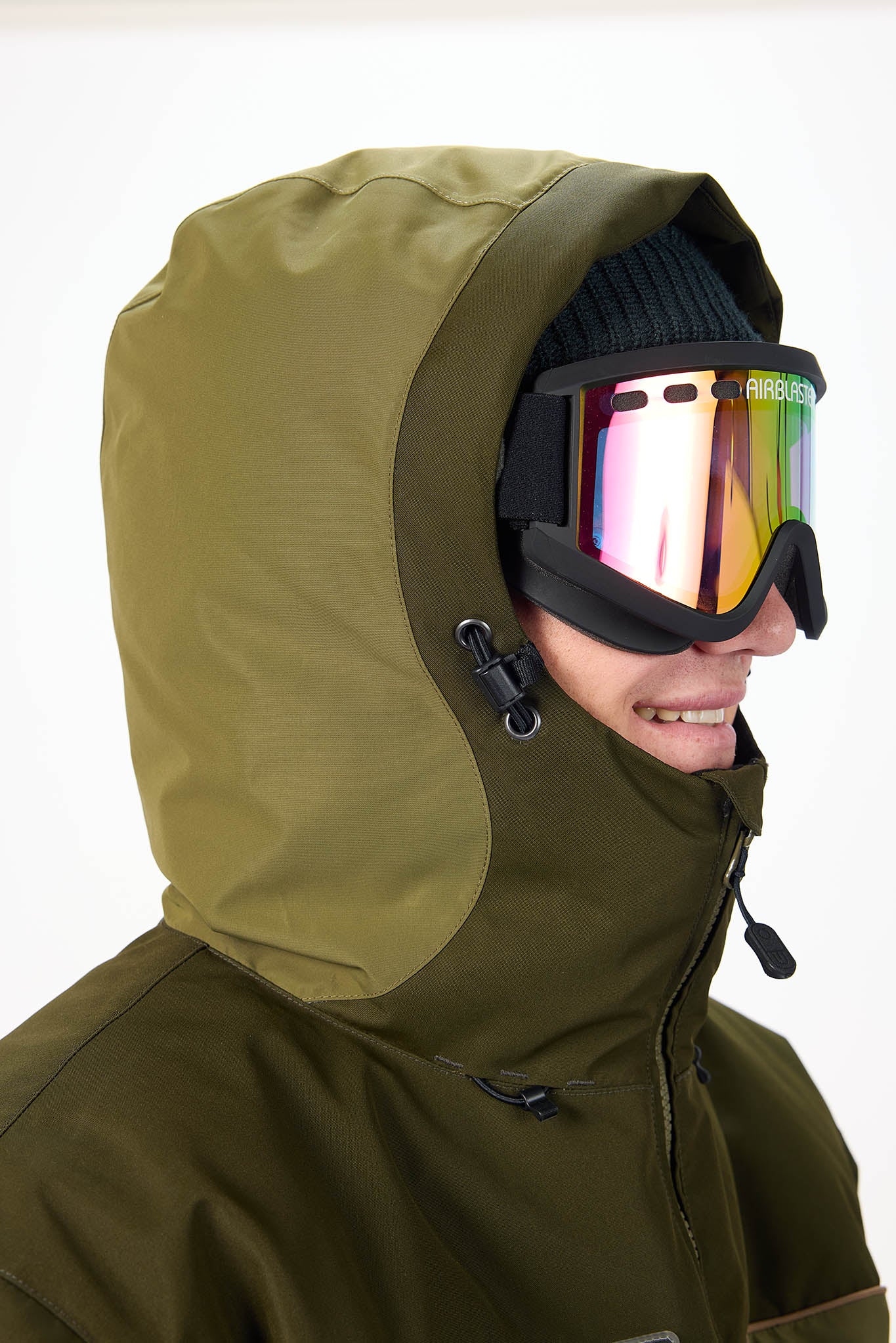 Person wearing a green hooded jacket and colorful goggles on a white background