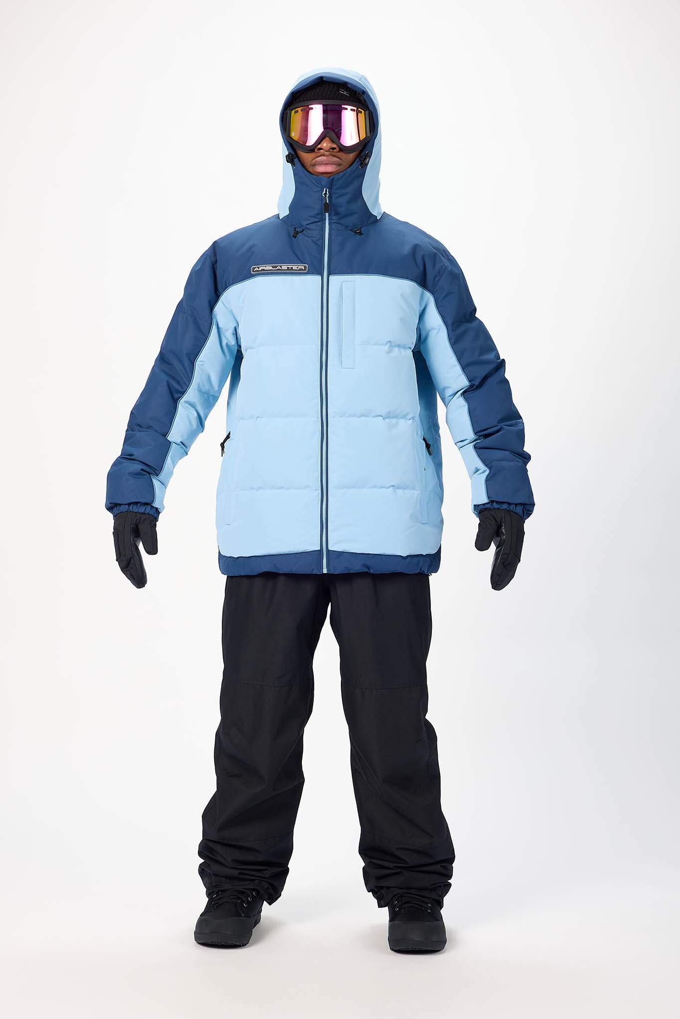 Person wearing a blue and navy ski jacket with black pants on a white background