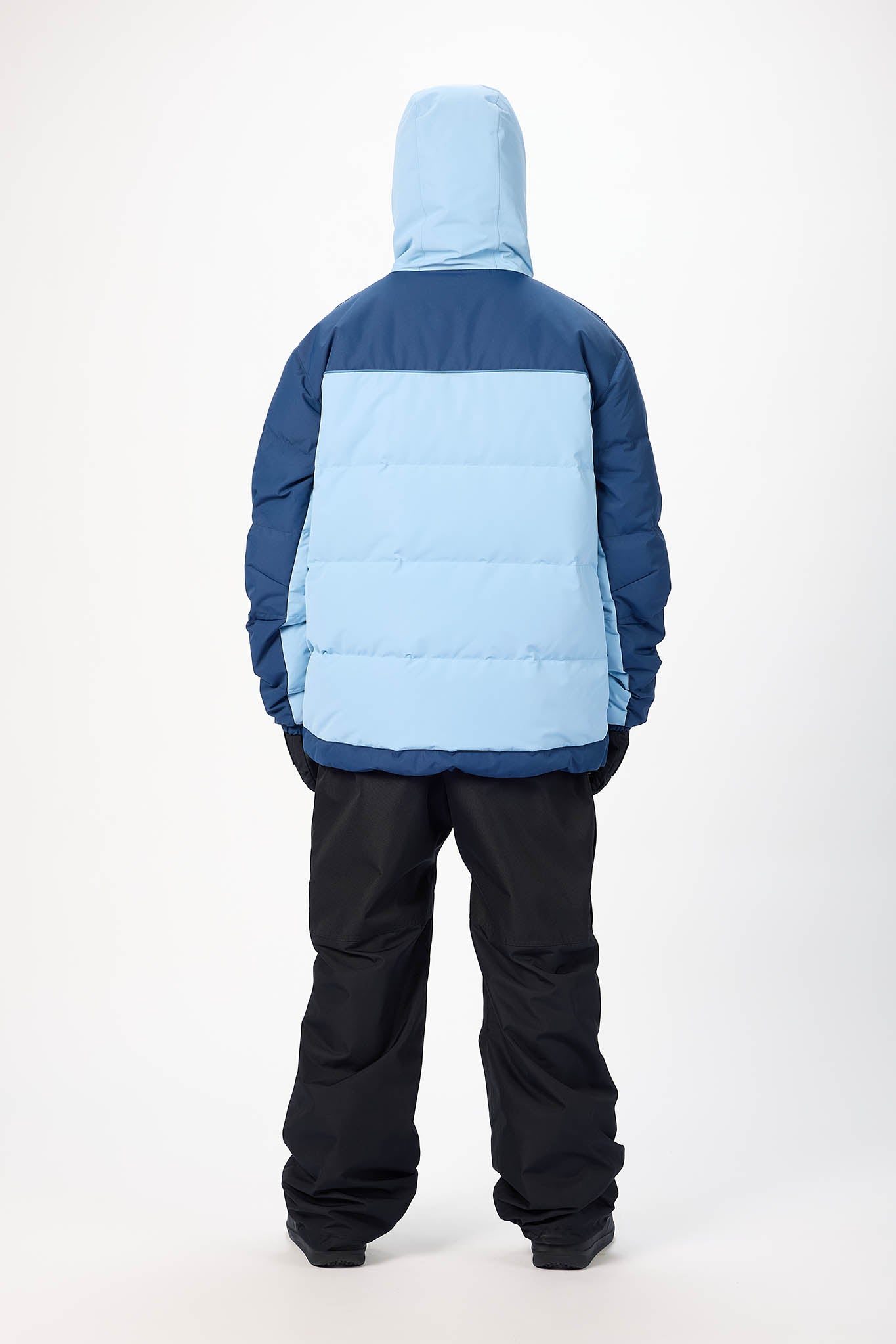 Person wearing a blue and navy insulated jacket with black pants on a white background