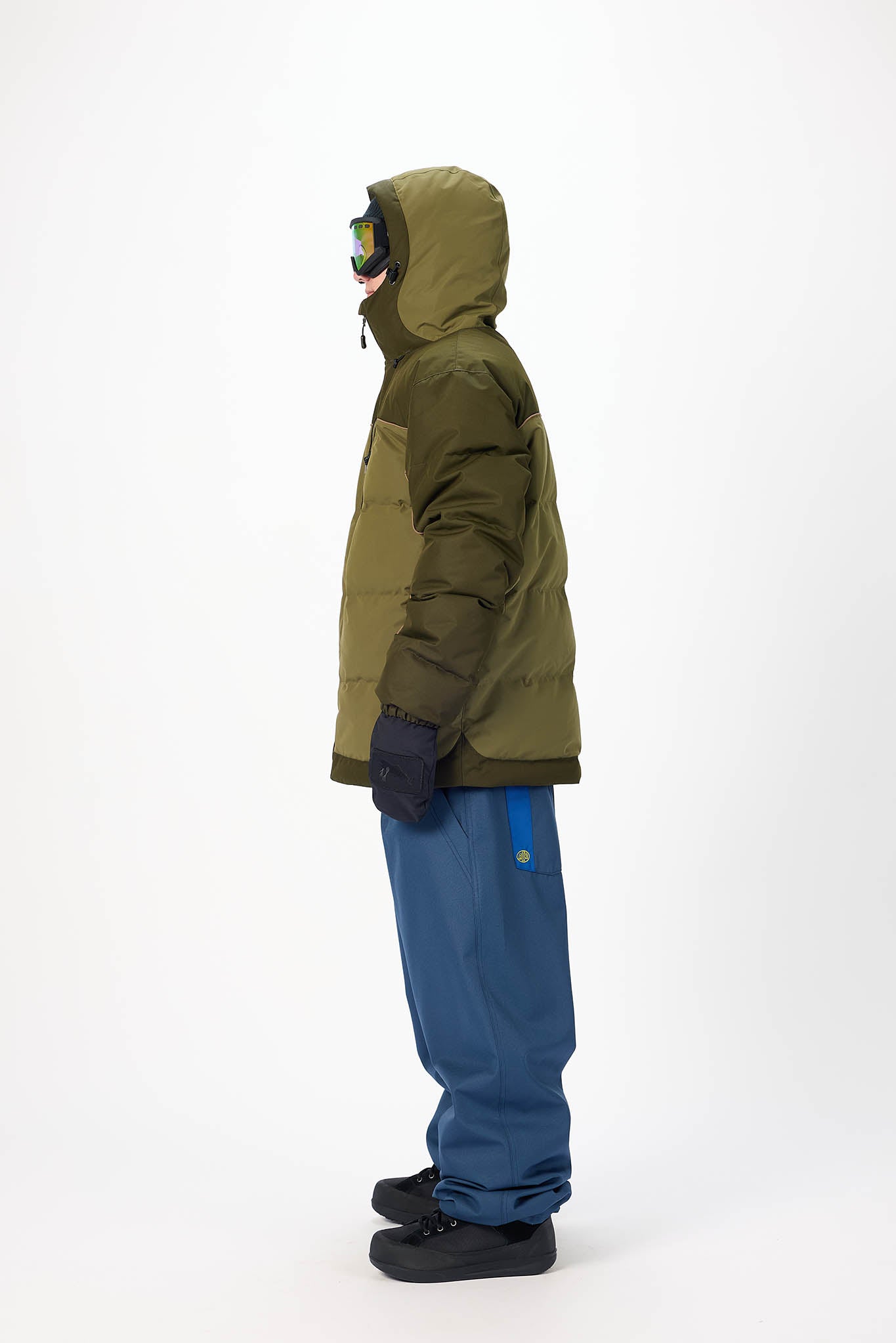 Person wearing a green jacket and blue pants on a white background
