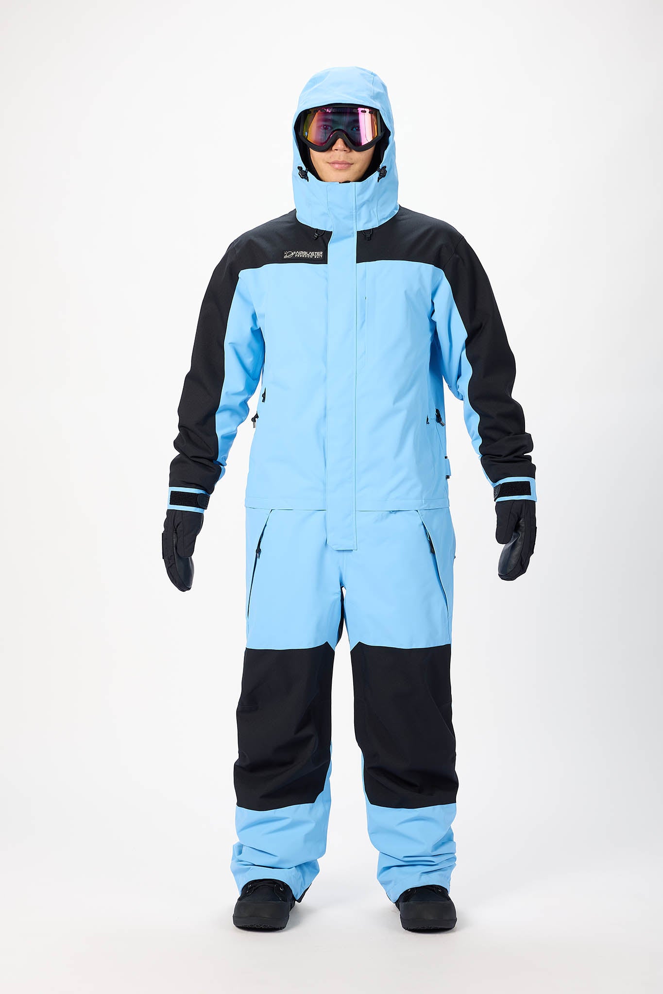 Person wearing a blue and black snowsuit with goggles on a white background