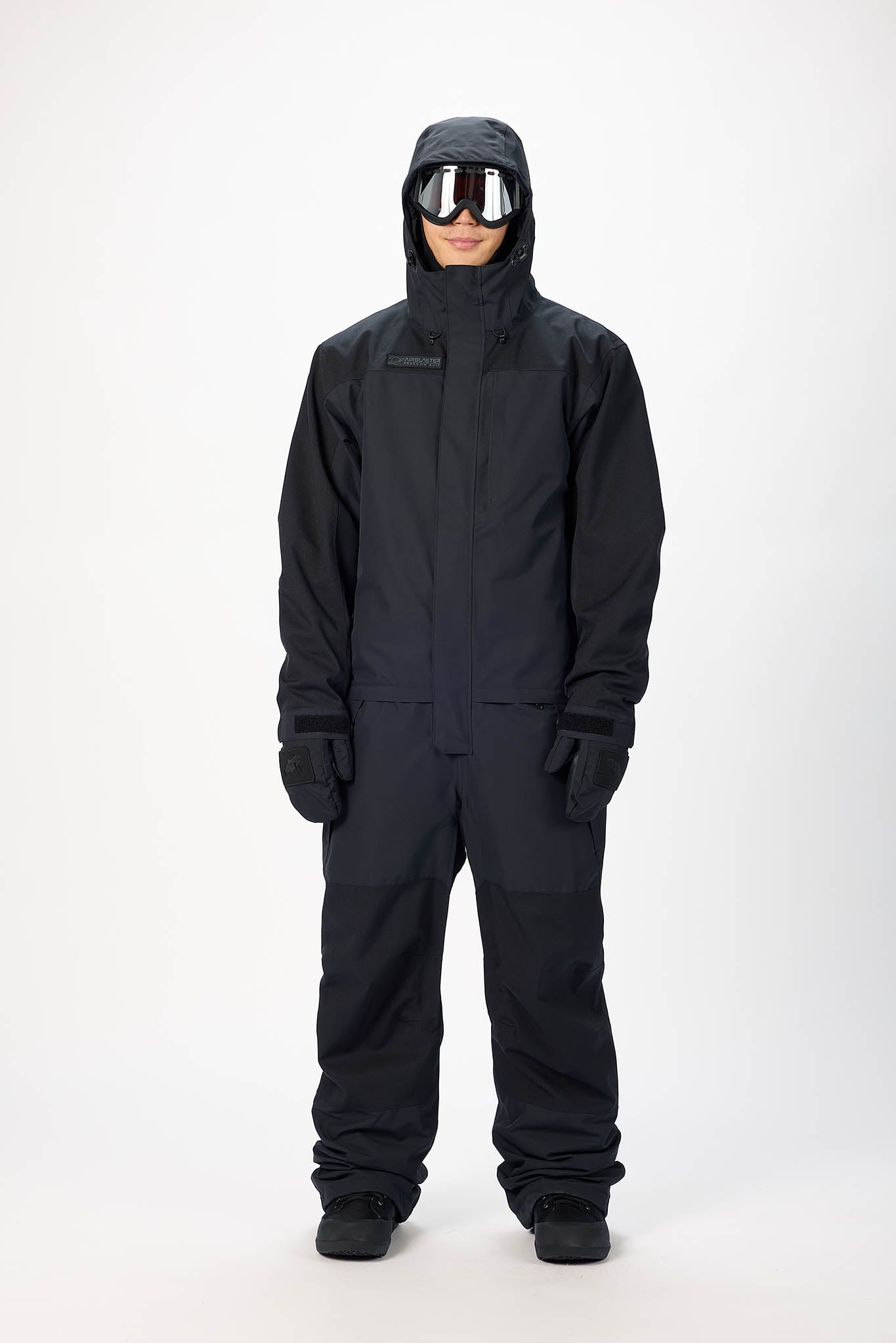 Person wearing a black snowsuit with goggles on a white background