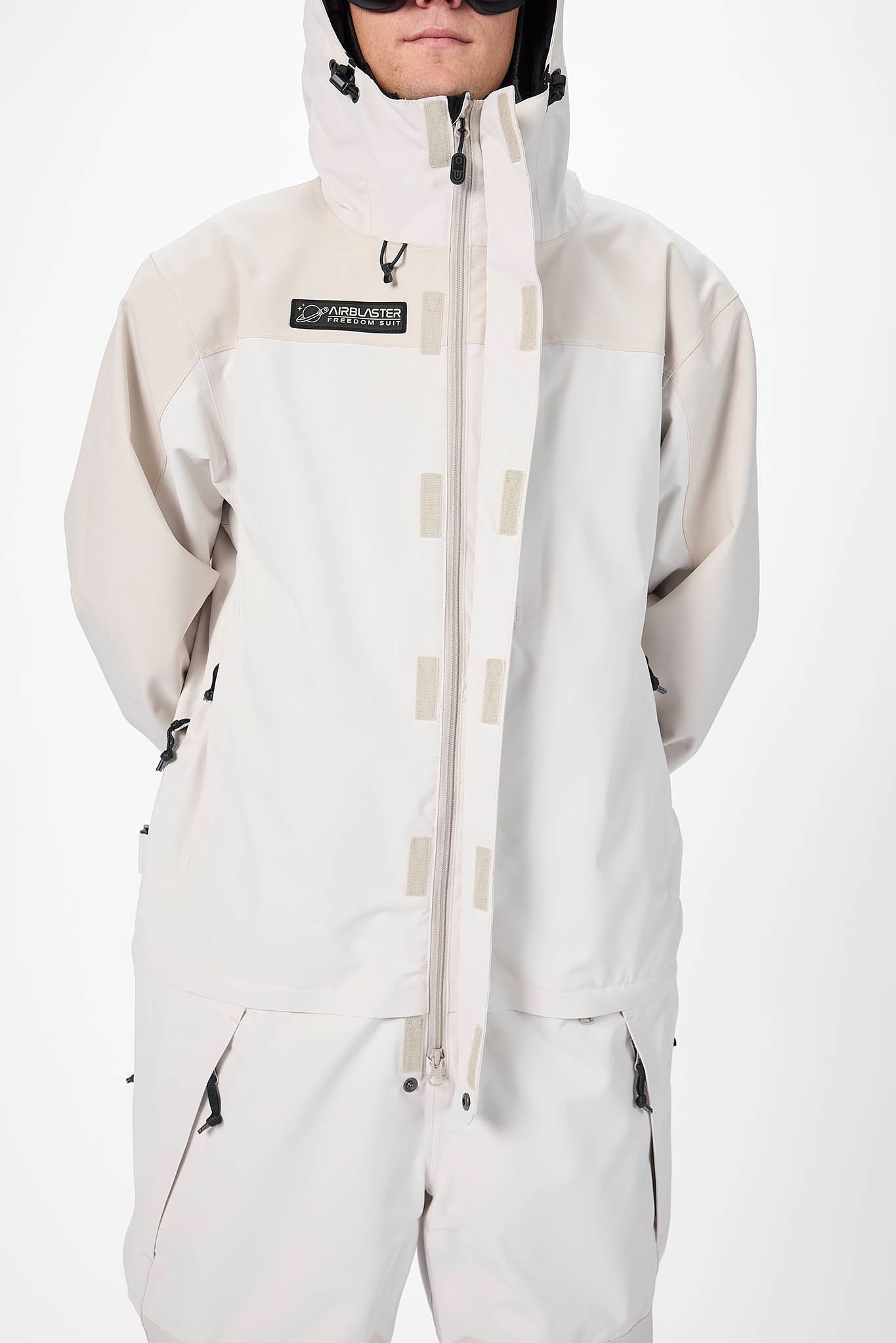 Person wearing a light gray snowsuit with a brand logo on a white background