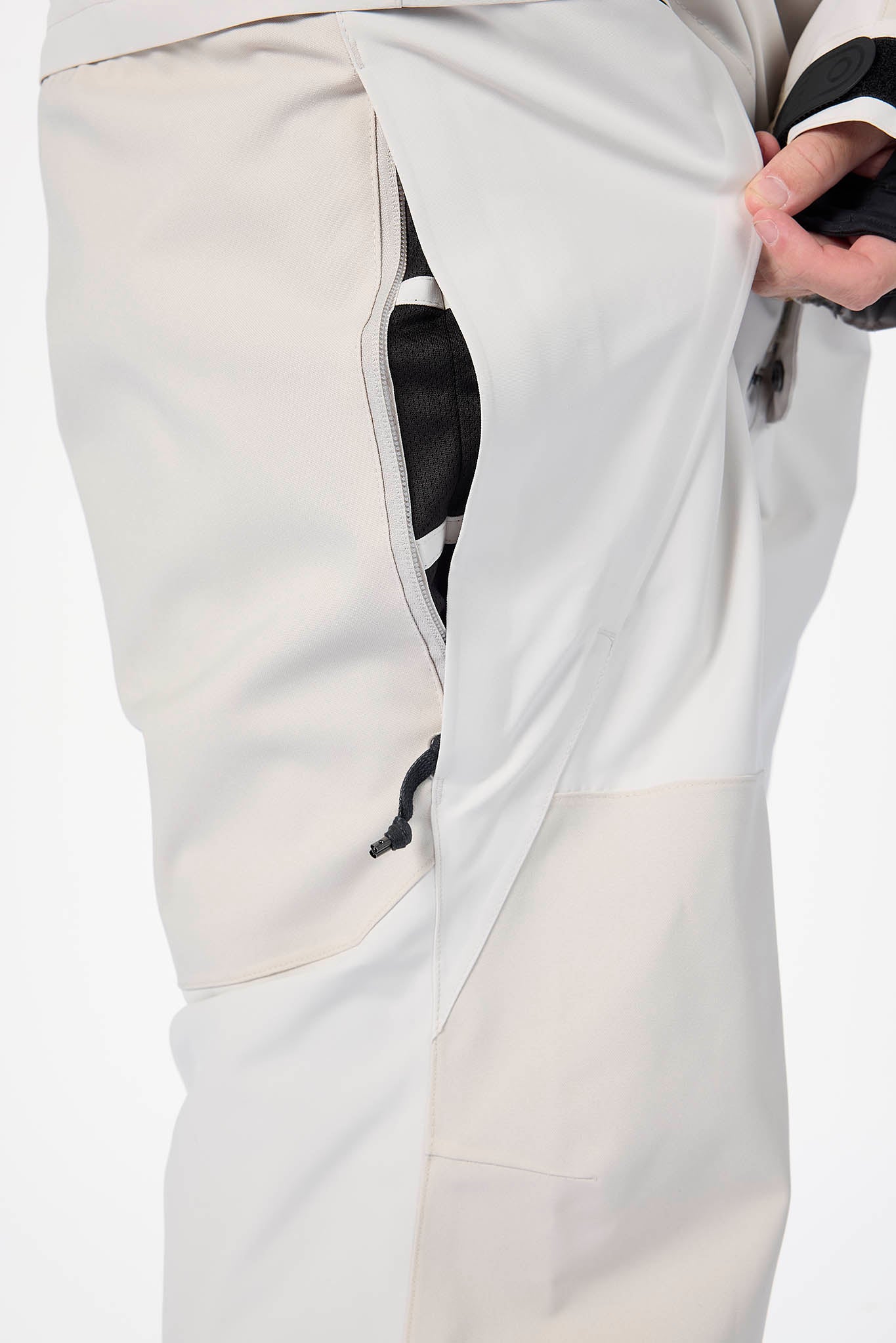 Close-up of light gray pants with a brand logo on a white background