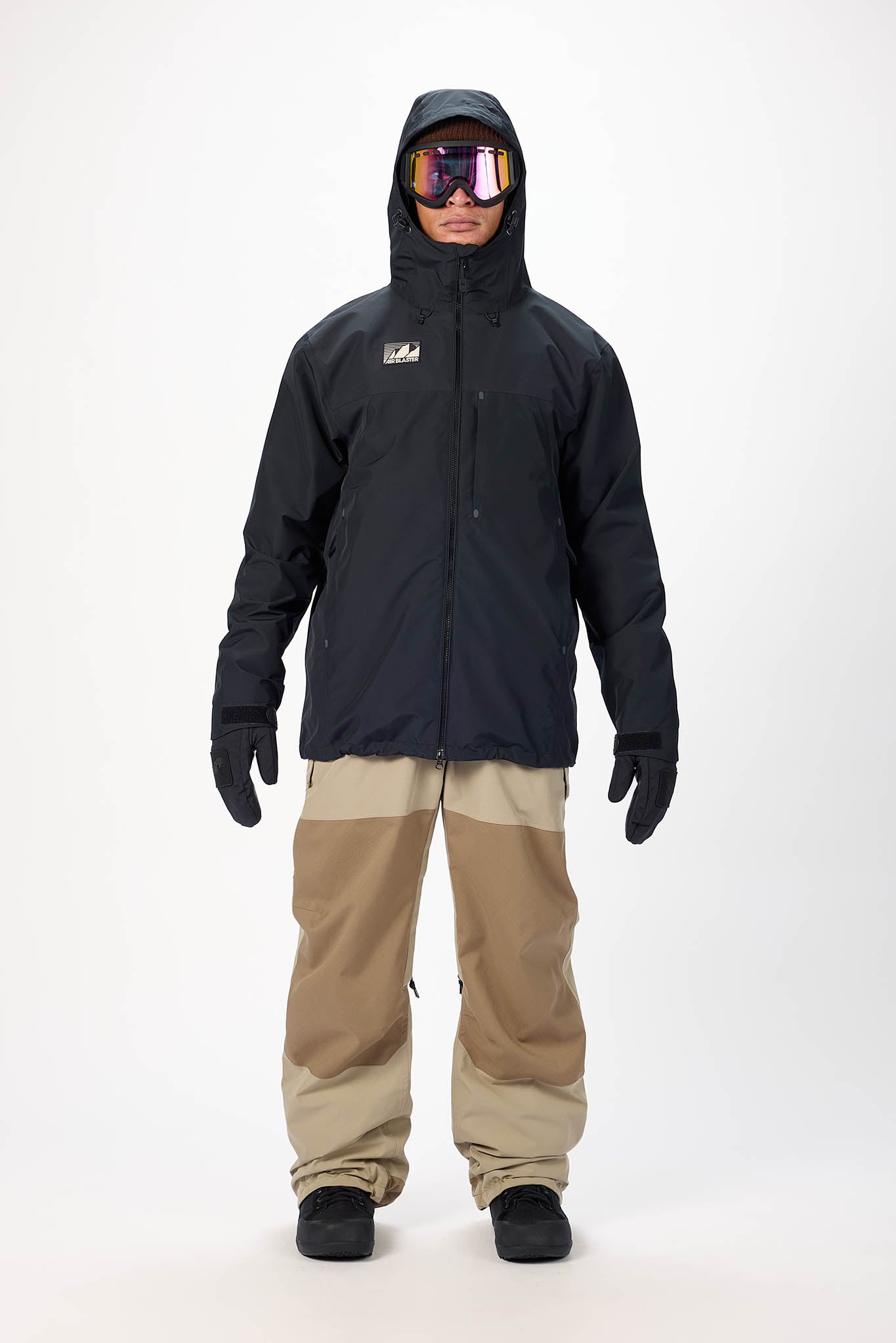 Person wearing a black snow jacket and tan pants with goggles on a white background