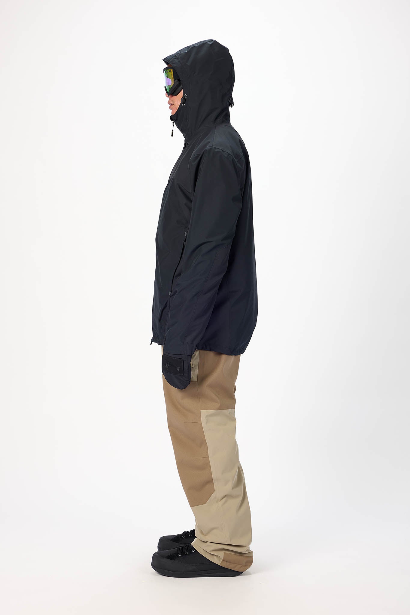 Person wearing a black jacket and beige pants on a white background