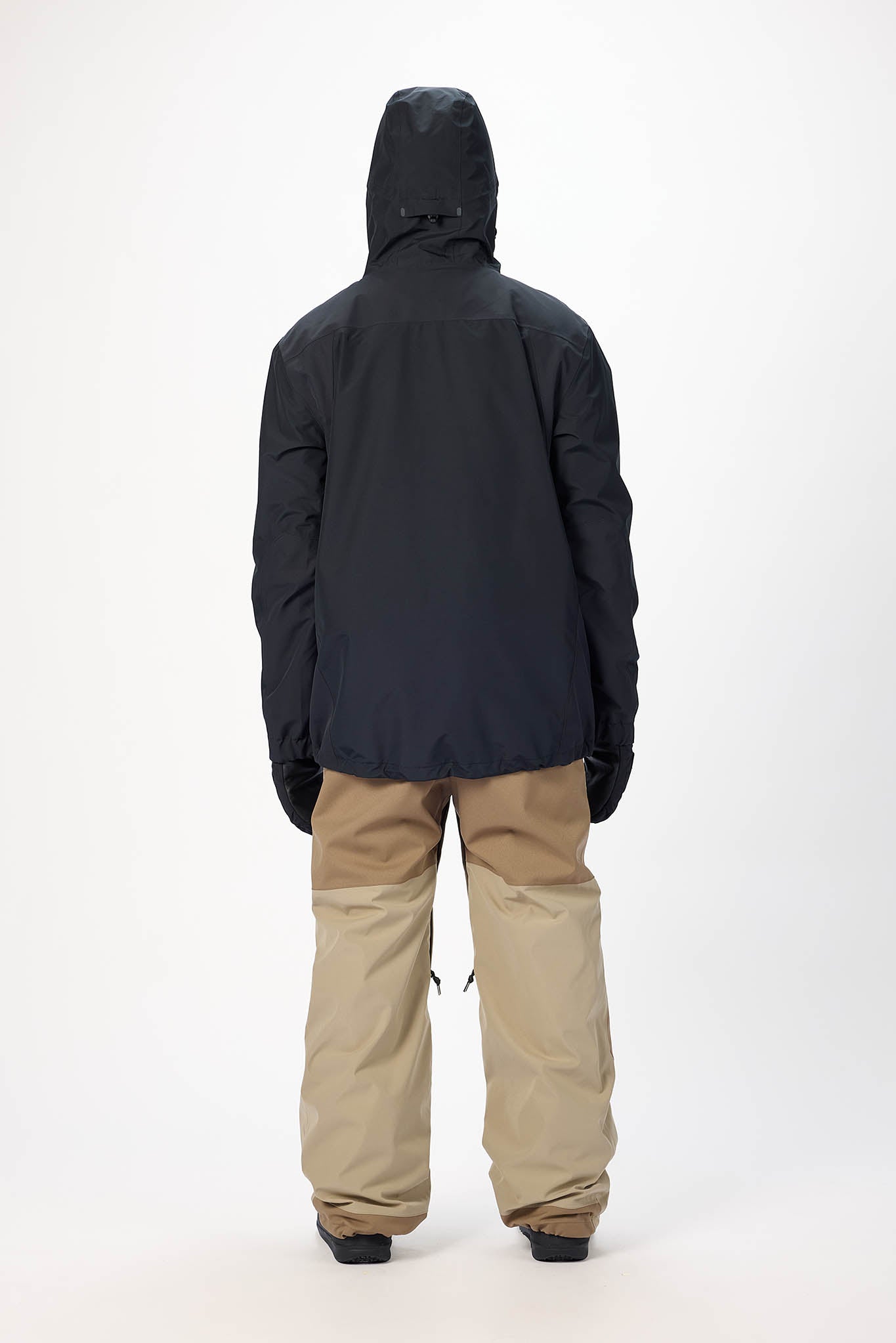 Person wearing a black jacket and beige pants on a white background