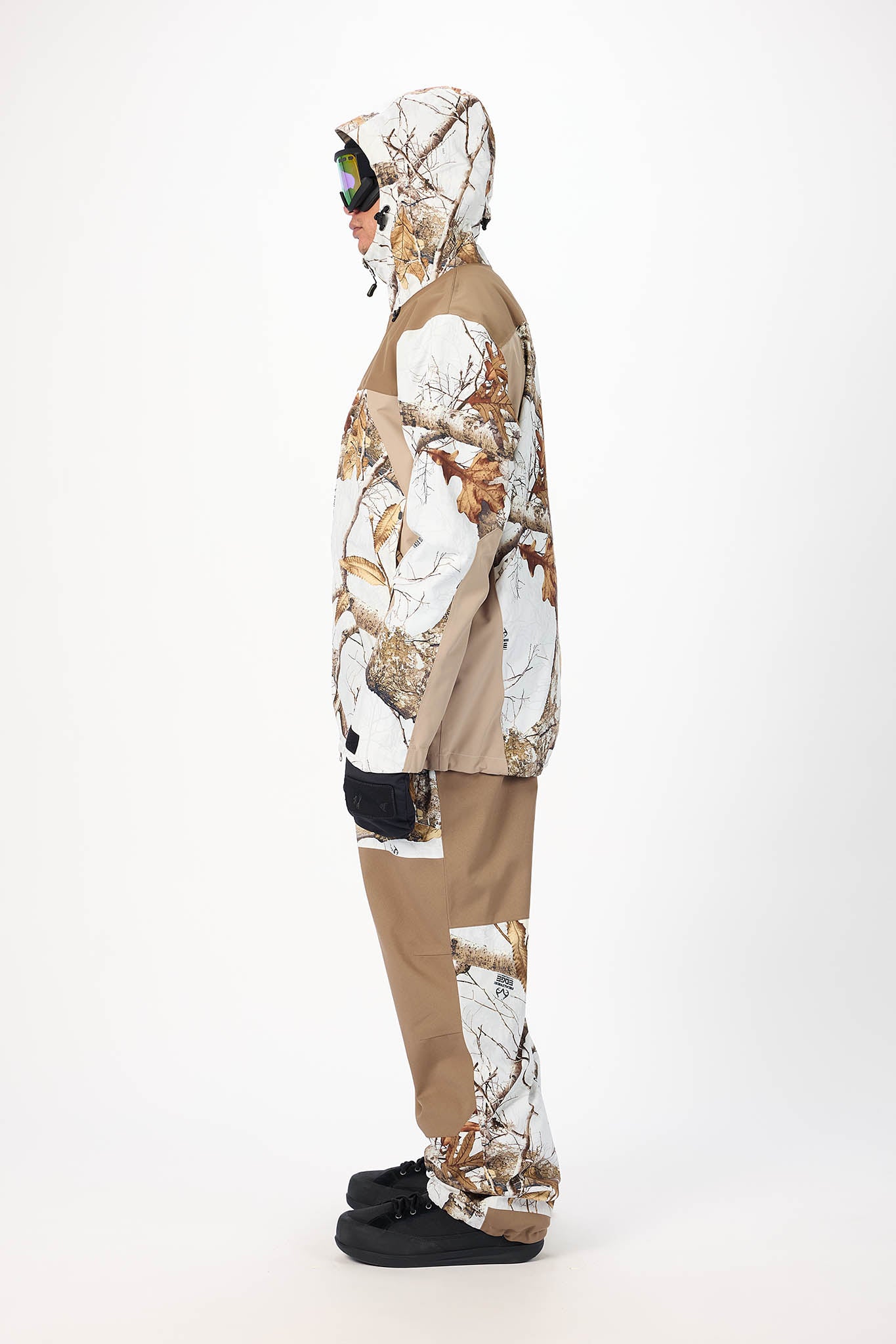 Person wearing a camouflage snowsuit with a hood on a white background