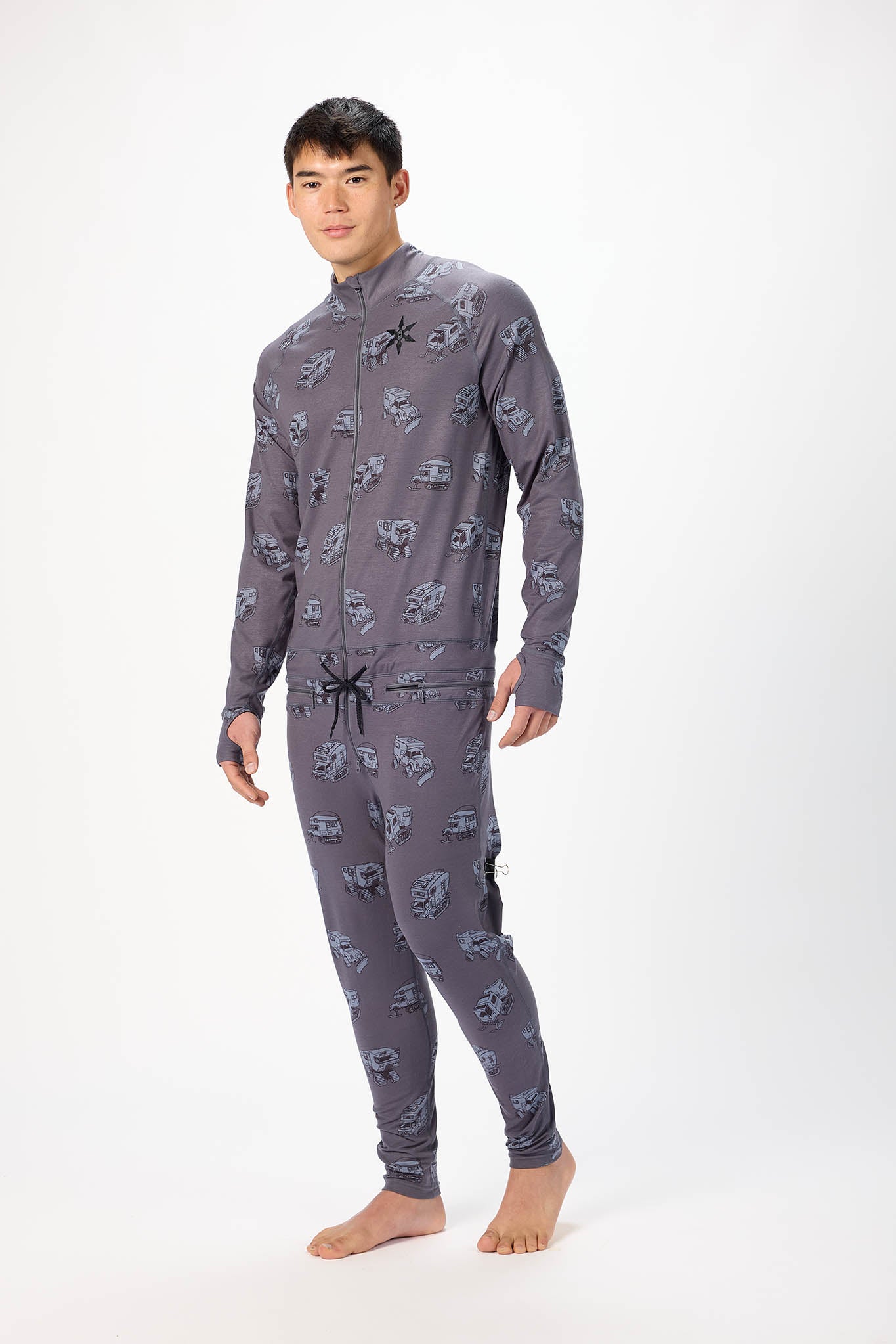 A man modeling a one piece thermal base layer suit, photographed against a seamless white studio background.