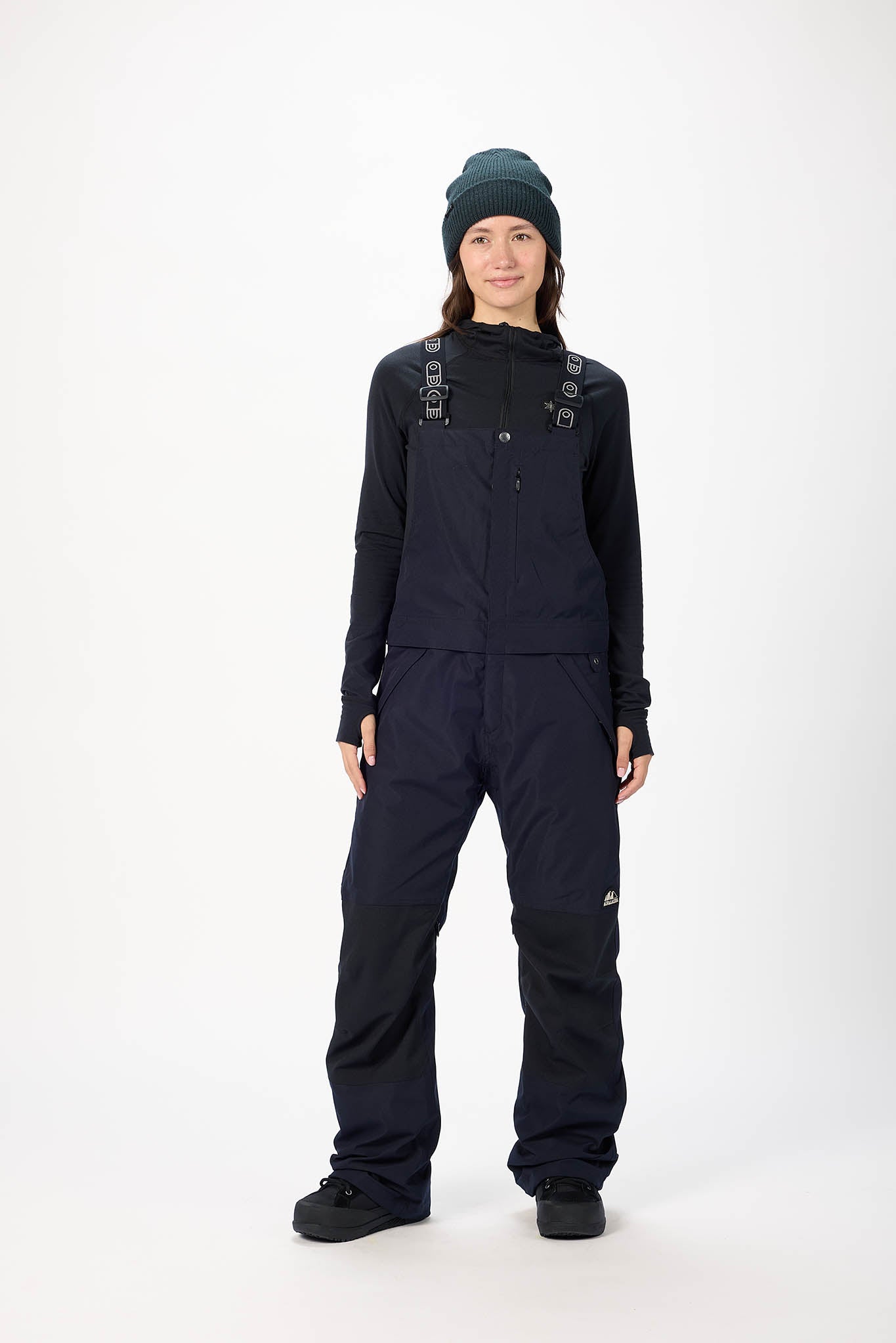 Person wearing a black snowsuit with suspenders on a white background
