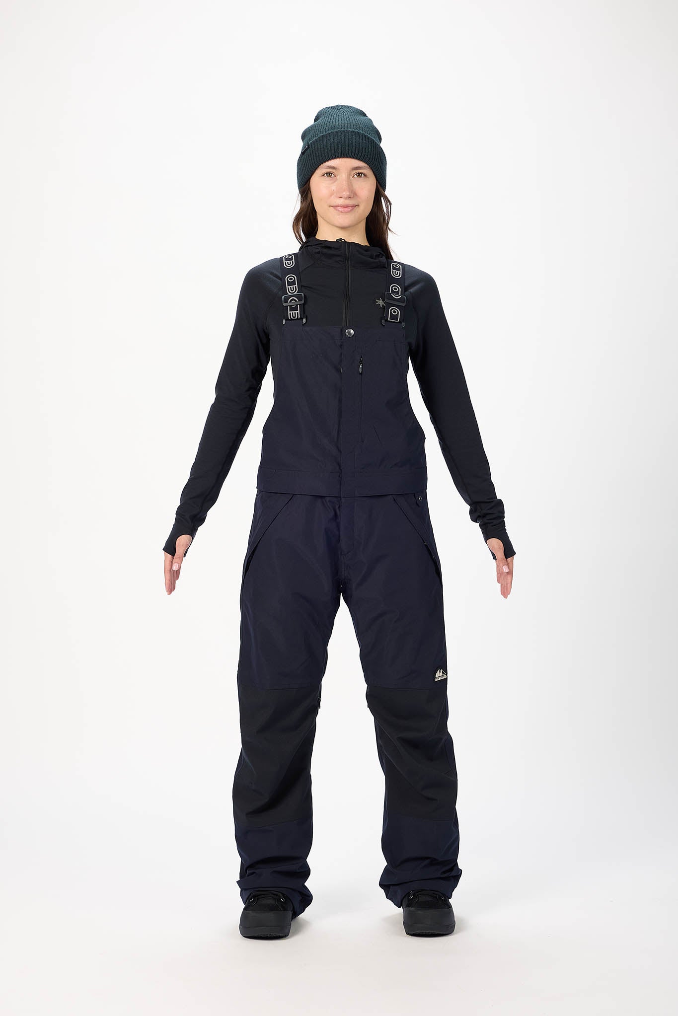 Person wearing a black snowsuit with suspenders on a white background