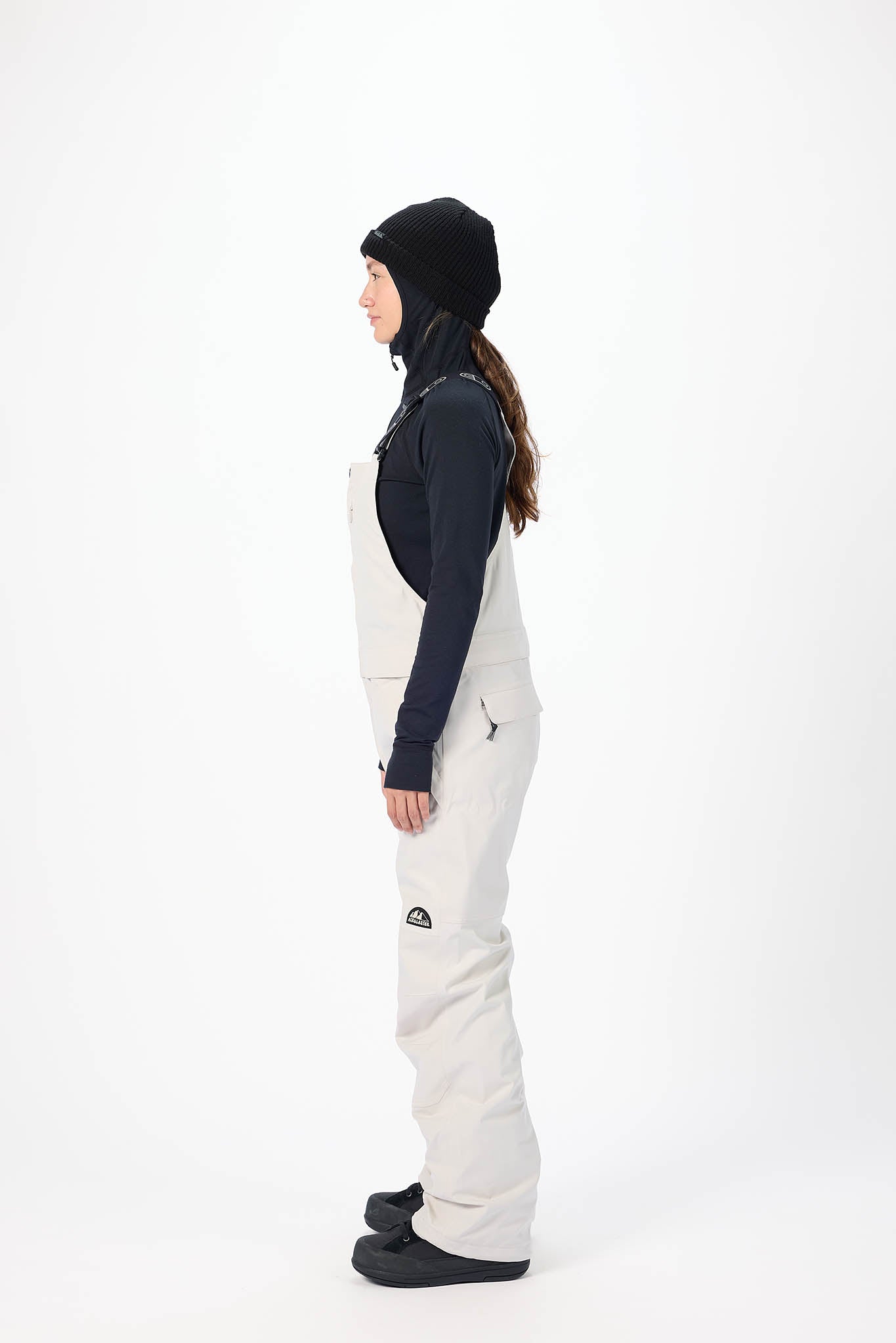 Person wearing a white snow pants and black jacket on a white background