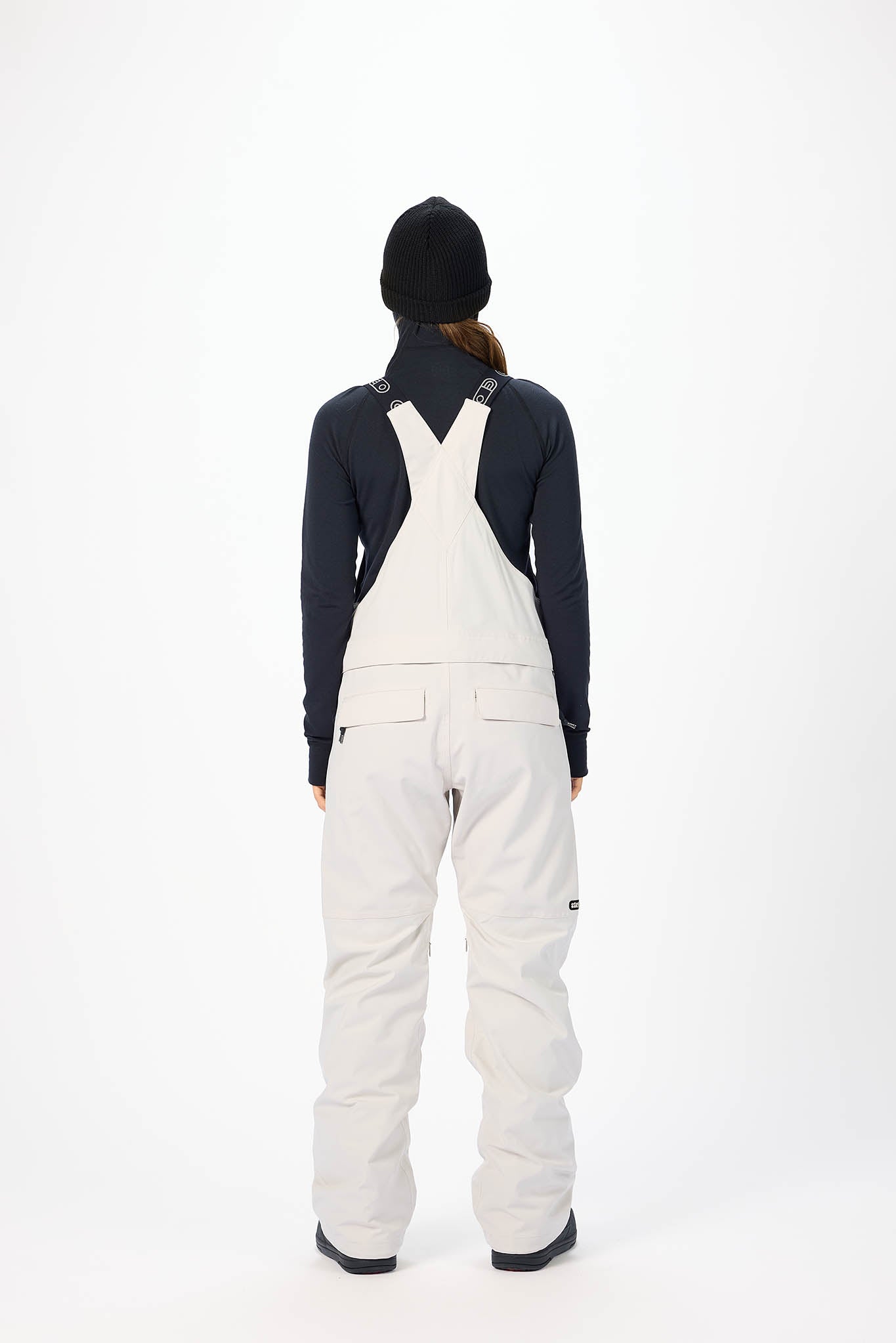 Person wearing white overalls and a dark jacket on a white background