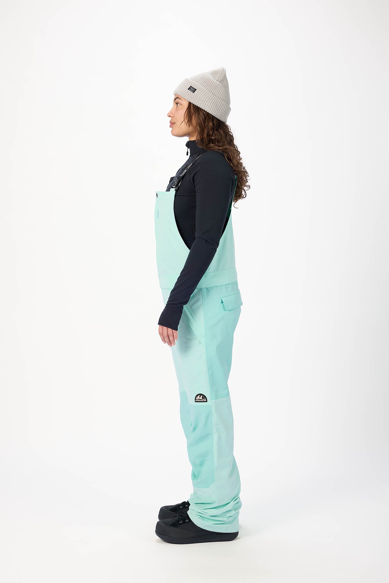 Person wearing a light blue snow pants and black jacket with a white background