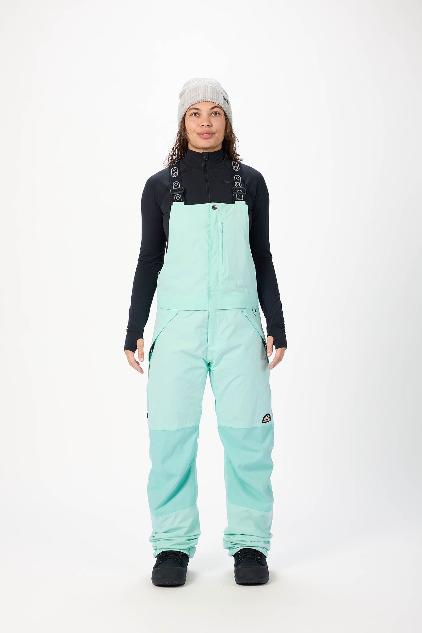 Person wearing light blue snow pants and a black long-sleeve shirt on a white background