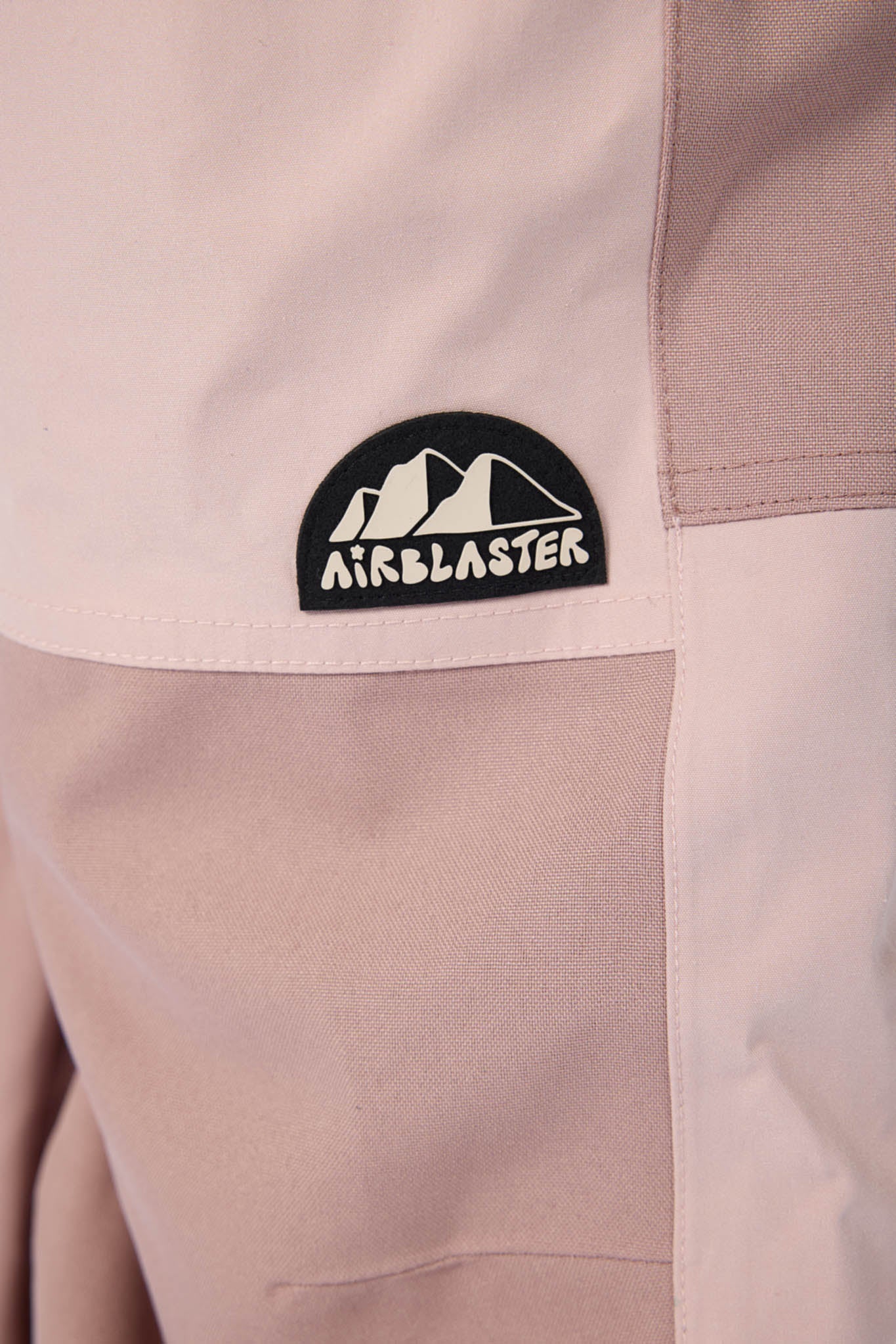 Close-up of a beige jacket with an Airblaster logo on a white background