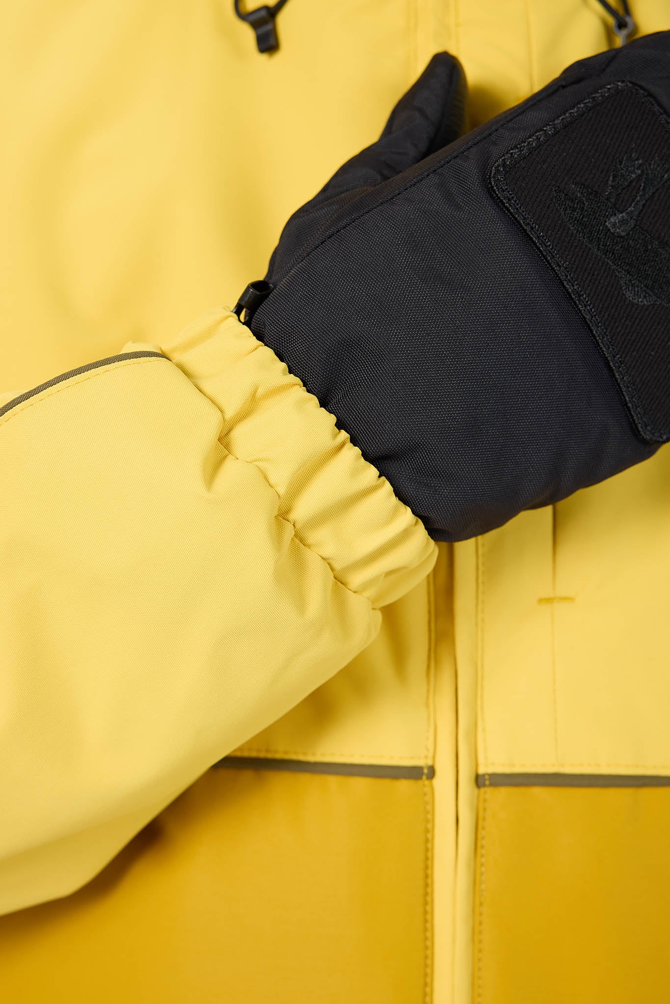 Close-up of a yellow jacket with a black glove on a blurred background