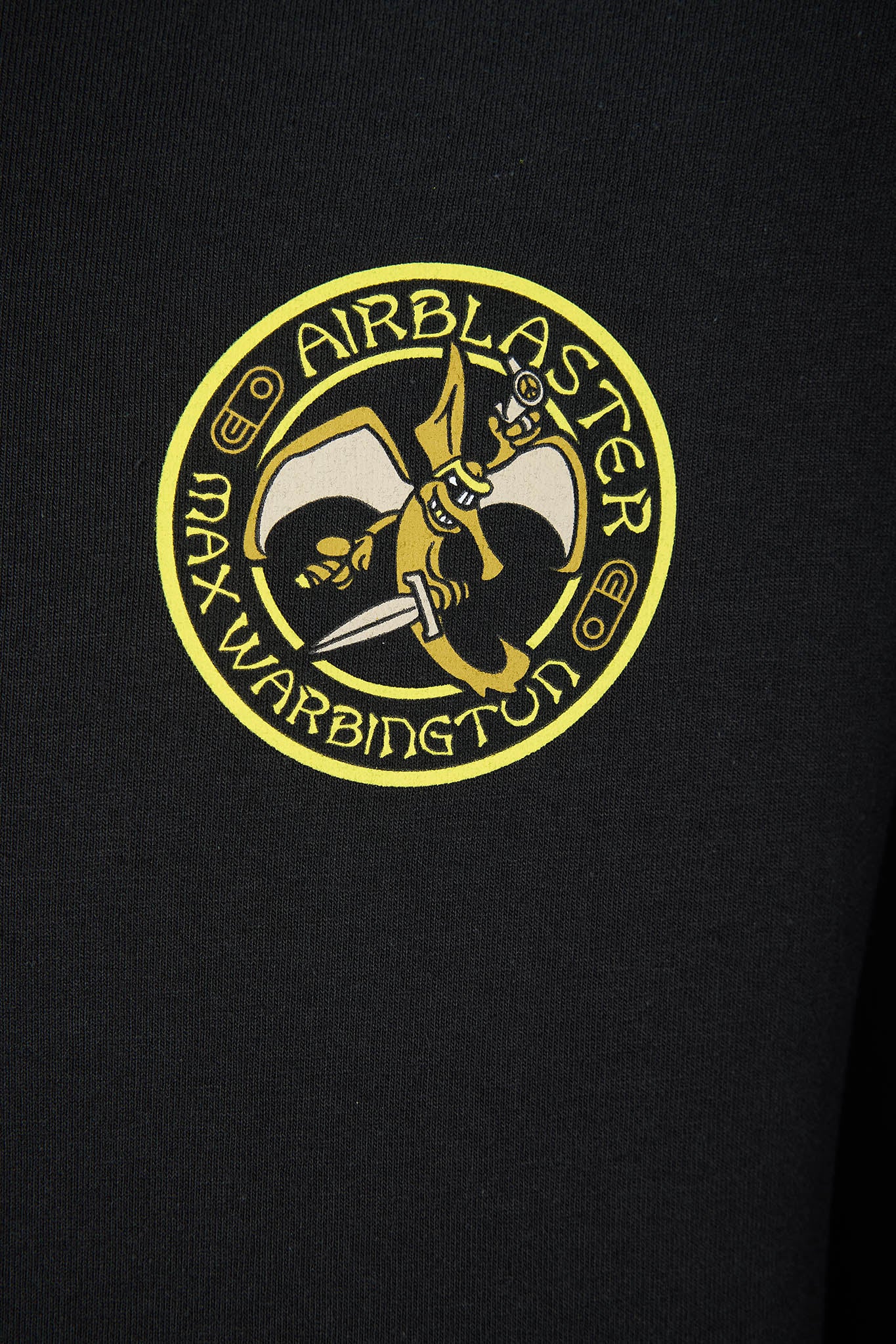A close-up of a black sweatshirt featuring a circular yellow and black graphic on the chest with the text 'AIRBLASTER MAX WARBINGTON' and a stylized character holding a sword.
