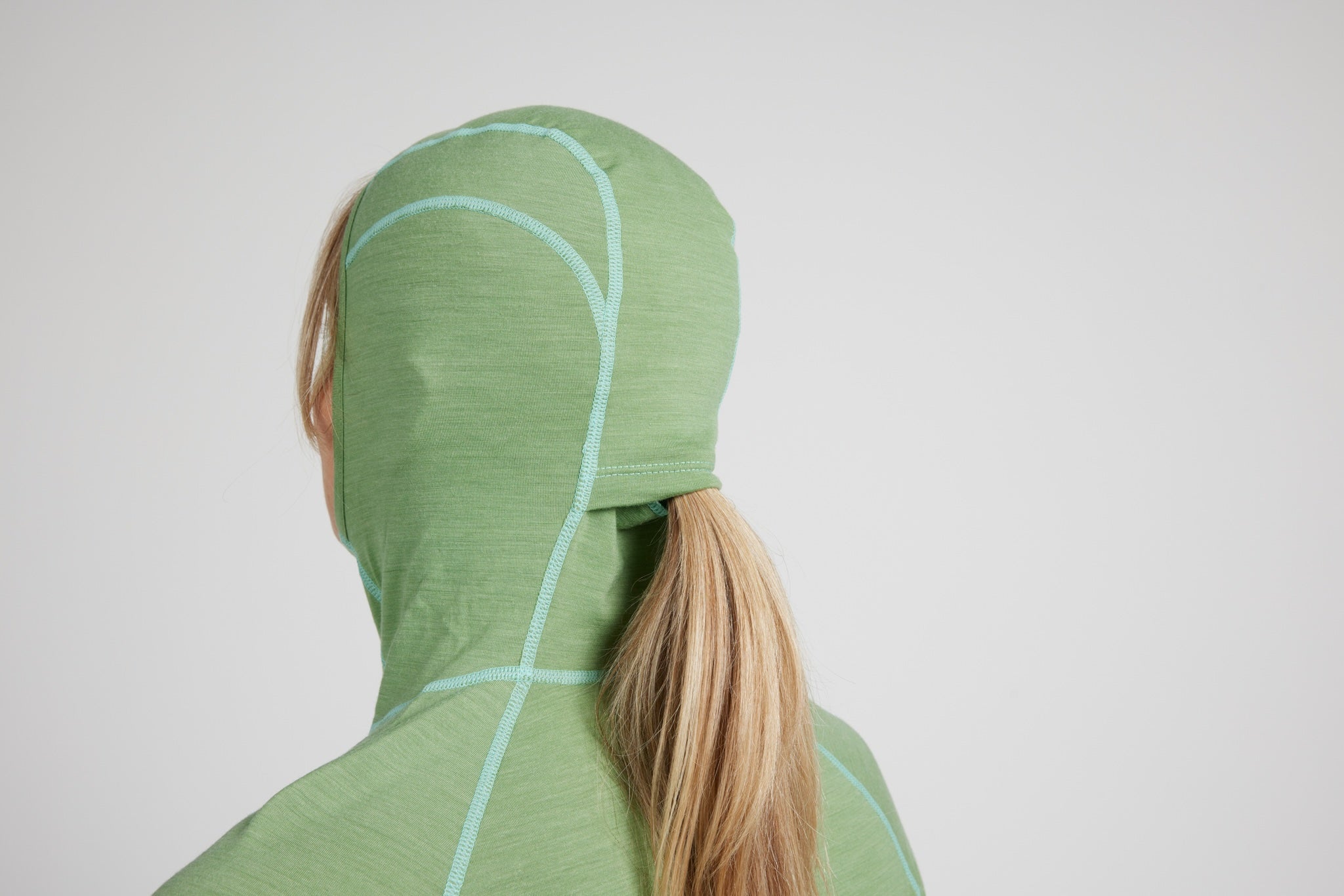 A person shown from the back wearing a light green hooded athletic jacket with light blue seam stitching, set against a plain light gray studio background.