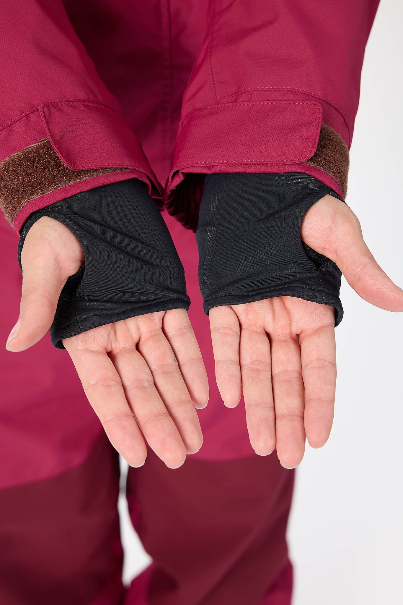 Person wearing a red jacket with black thumb grabbing on a white background