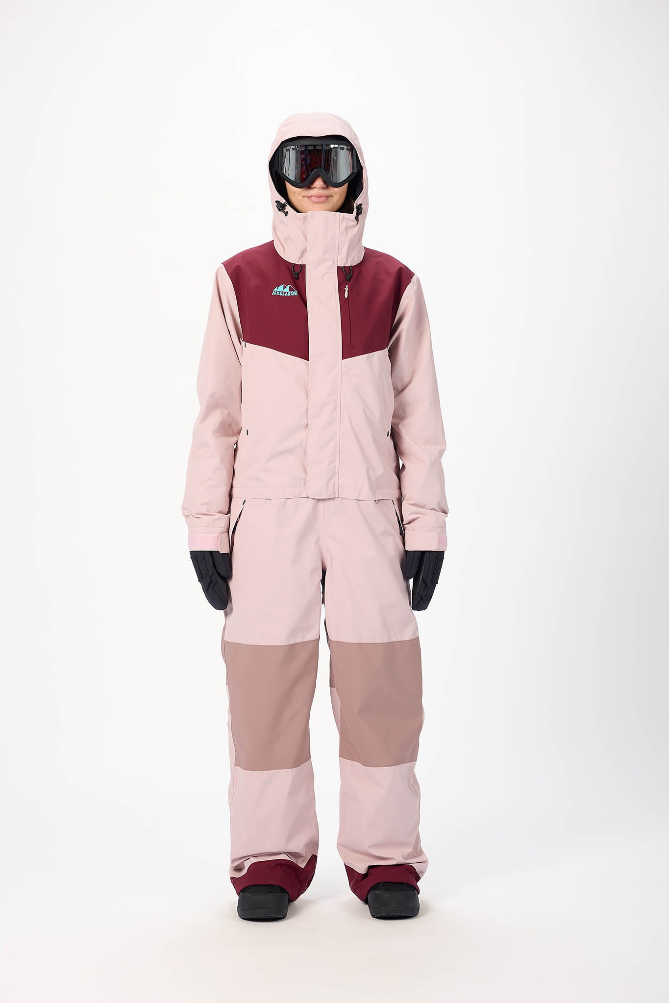 Person wearing a two-tone pink and maroon snowsuit on a white background