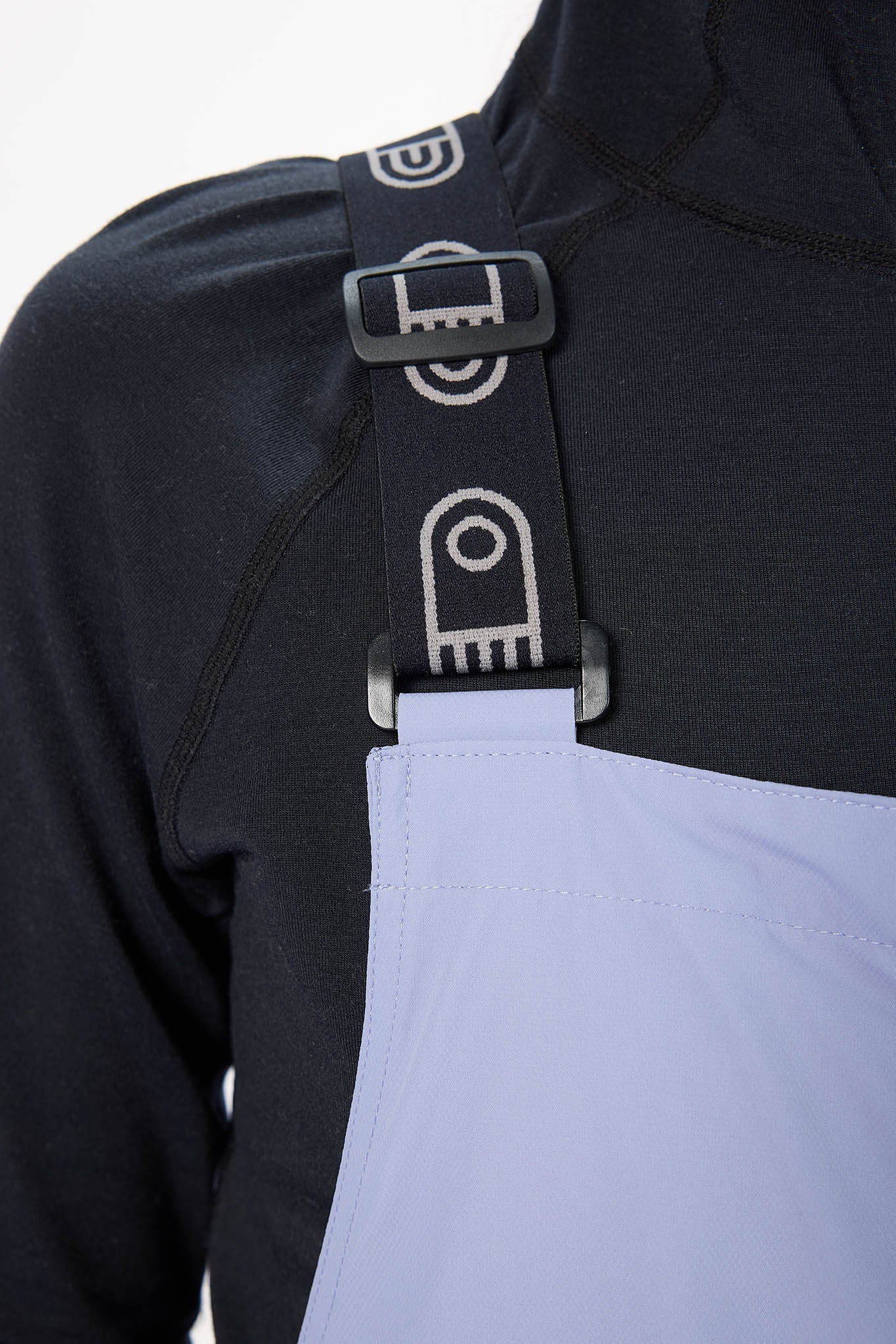 Close-up of a black jacket with gray straps and buckles on a light gray background
