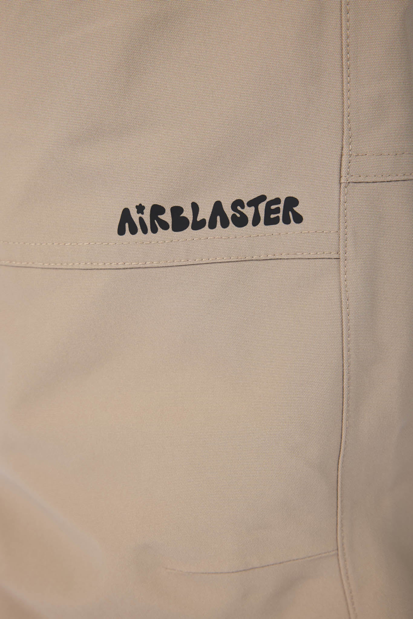 Beige fabric with 'Airblaster' logo embroidered on a pocket