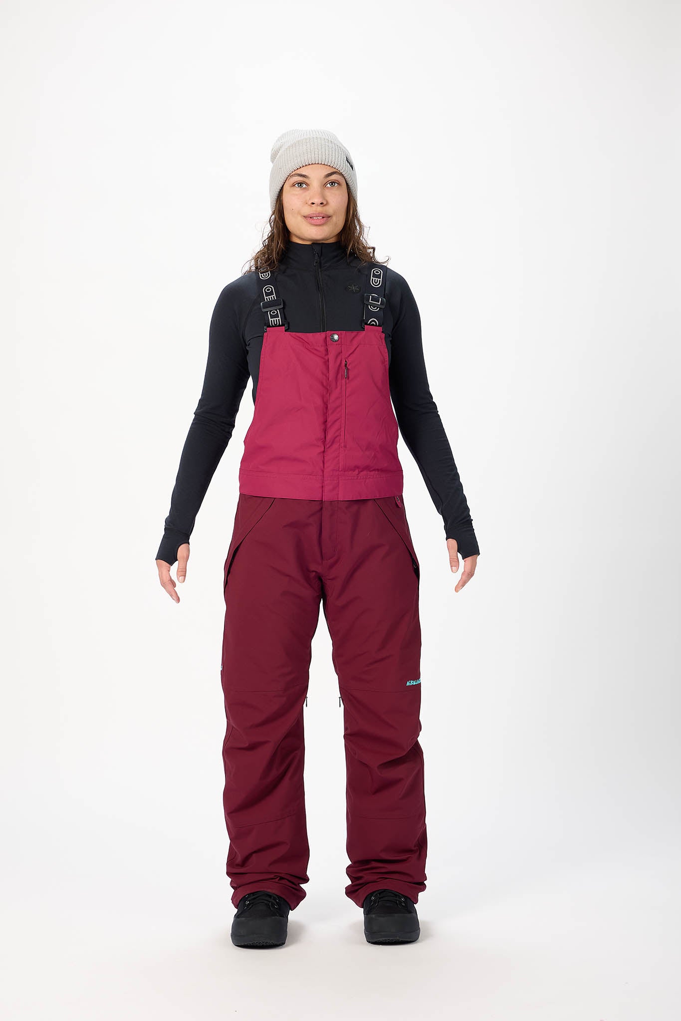Person wearing a maroon snowsuit with black top on a white background