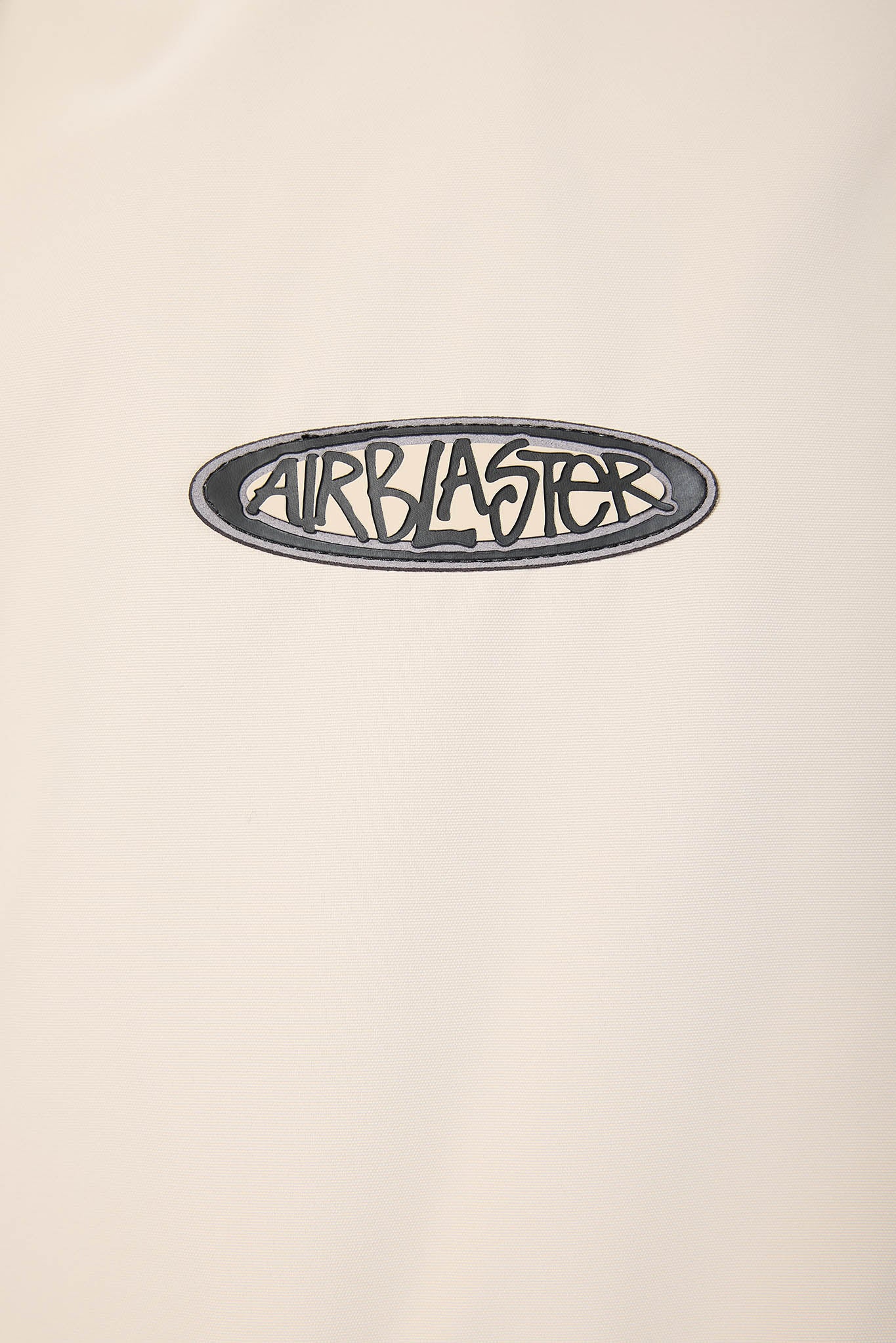 A close-up of a cream-colored surface featuring a black oval 'AIRBLASTER' logo decal.