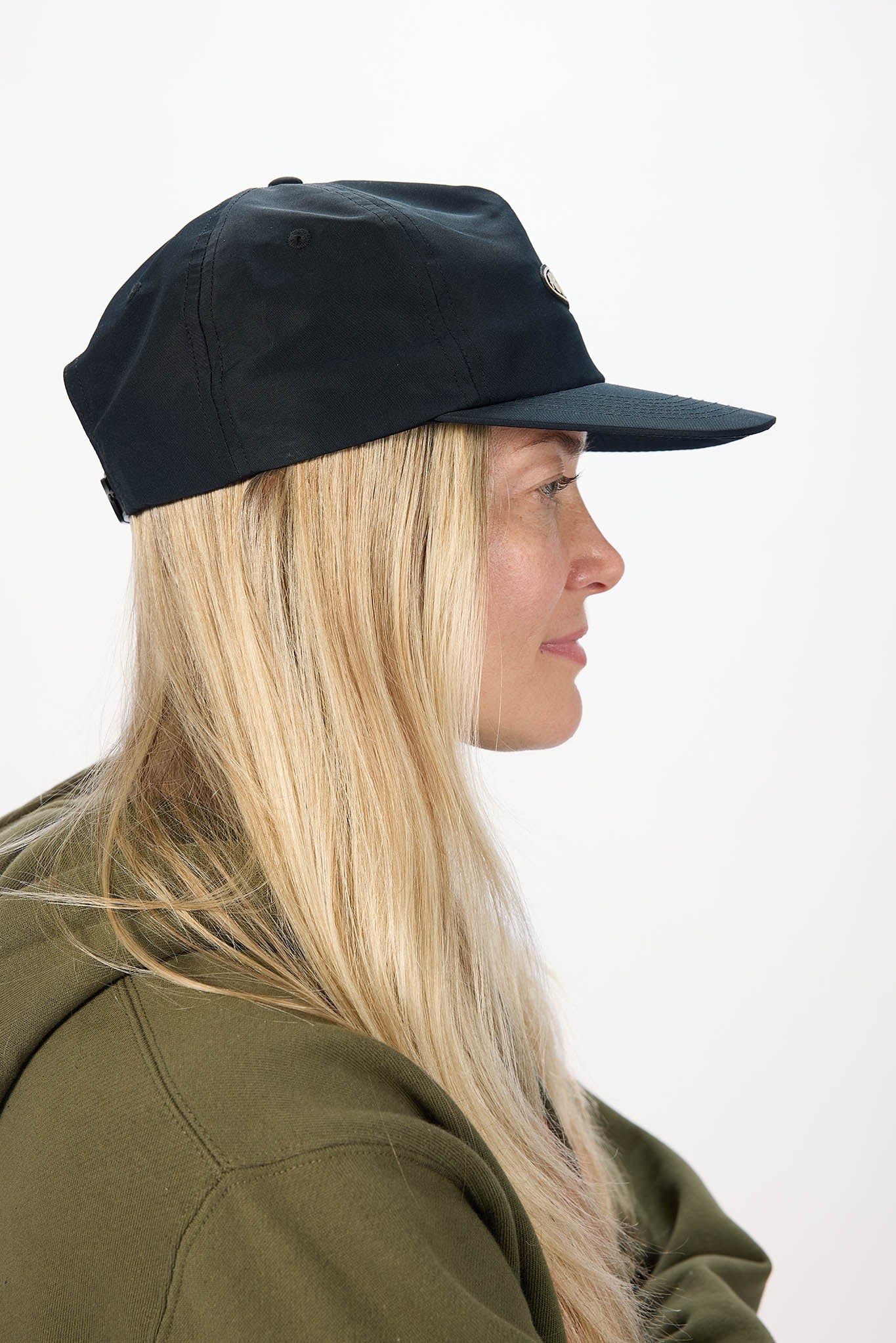 side profile of A woman with long blonde hair wearing a black baseball