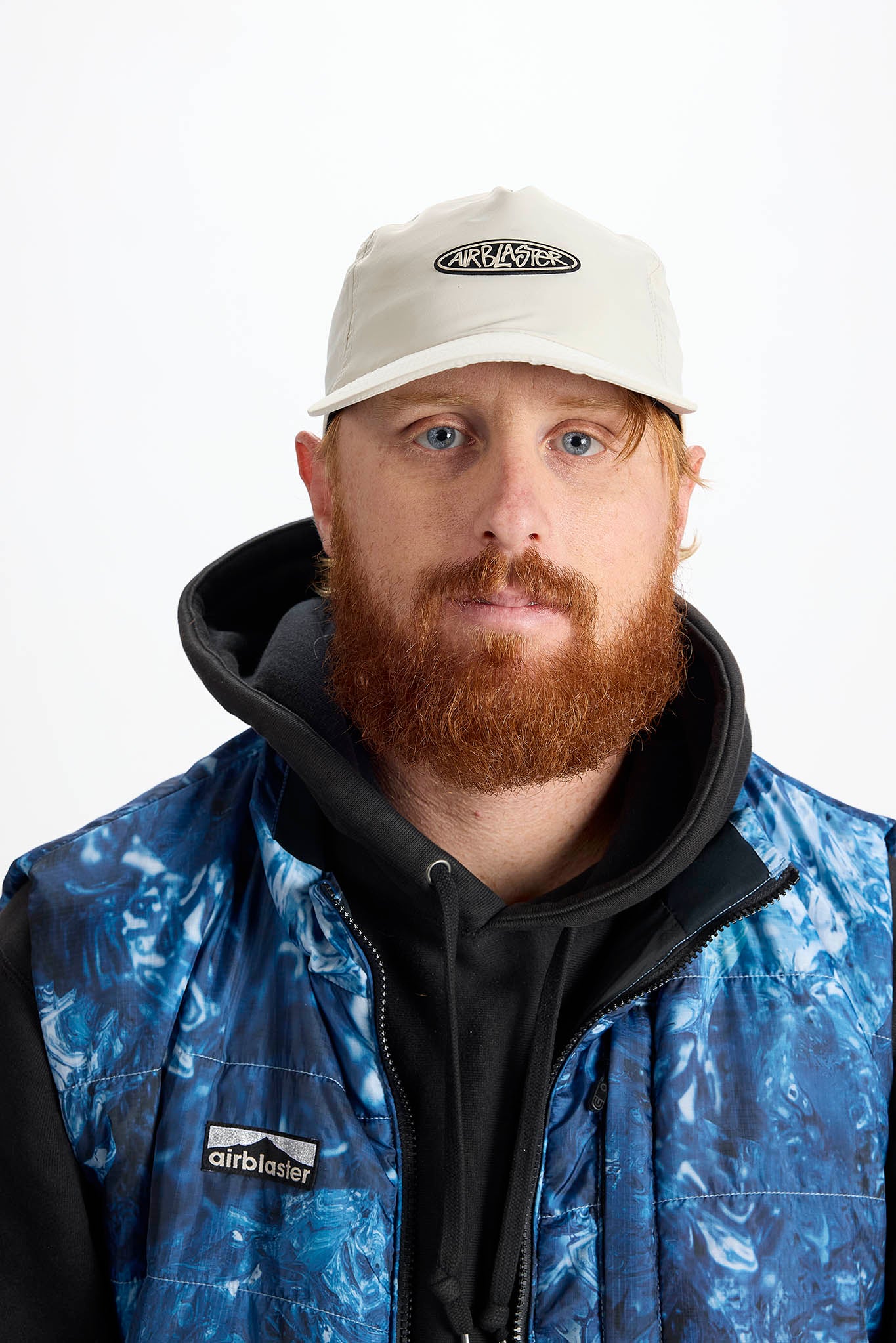 A man with a red beard wearing a white baseball cap photographed against a plain white background.