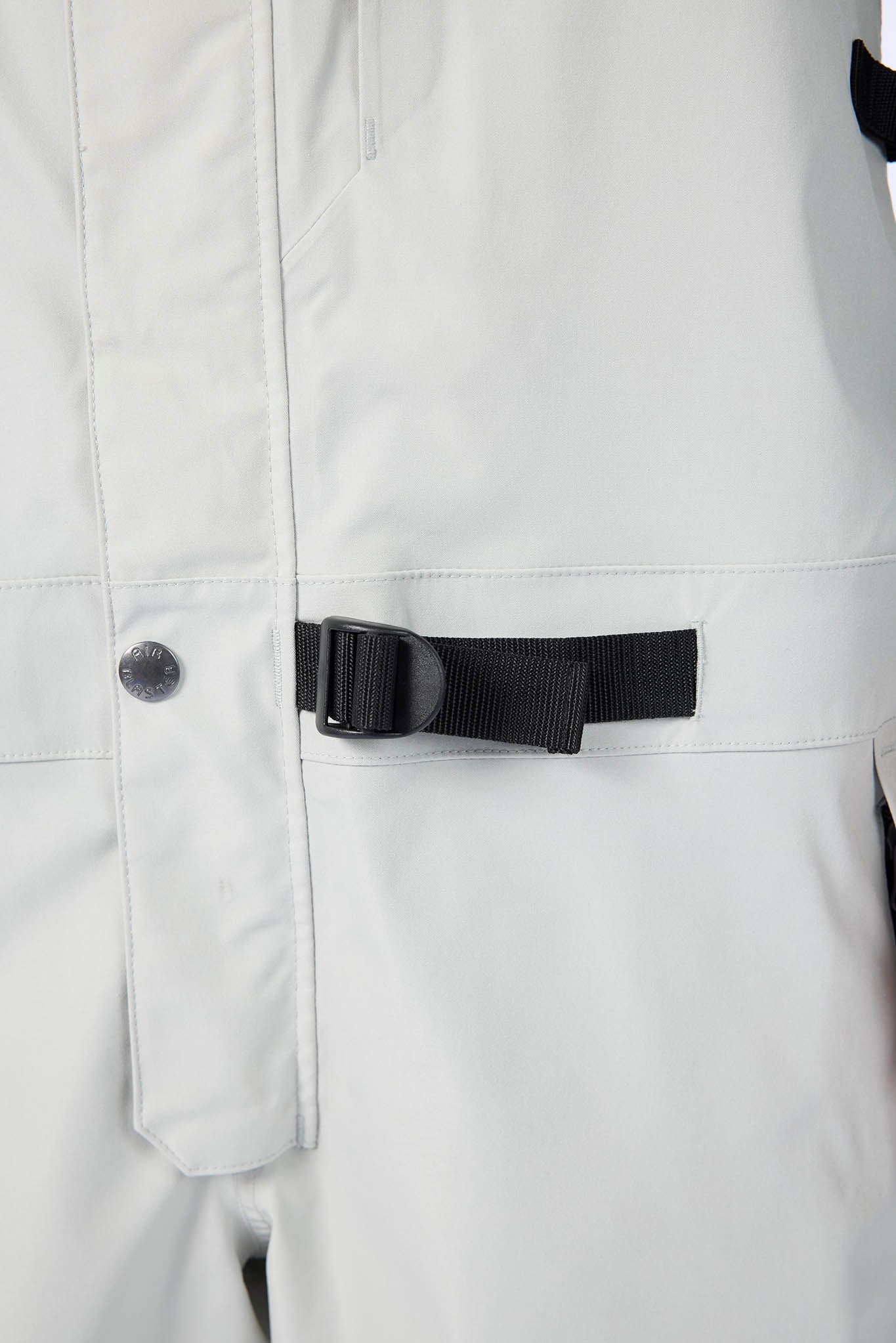 Close-up of a white jacket with a black zipper and button on a light gray background