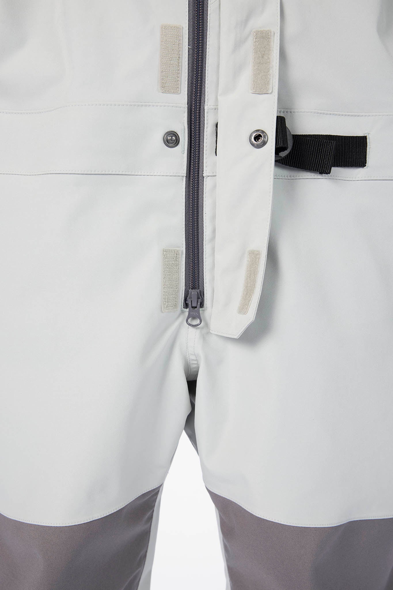 Close-up of a light gray jacket with zippers and buttons on a white background