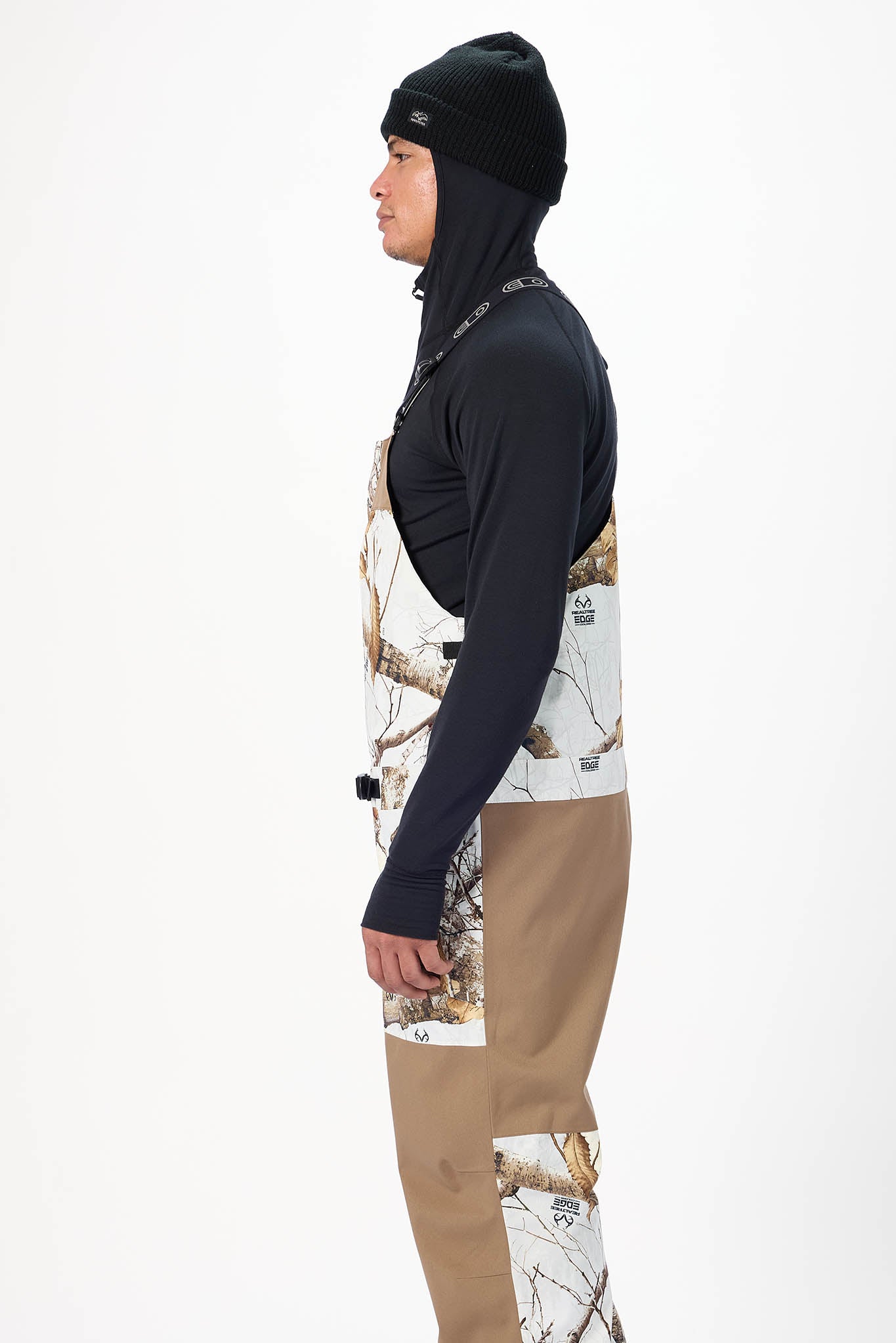 Person wearing a black hoodie, camouflage shirt, and tan pants on a white background