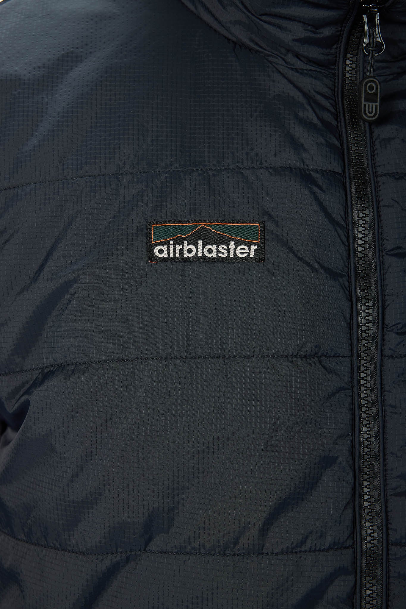 Close-up of a dark navy puffer jacket with a black zipper and a central Airblaster logo patch on the chest.
