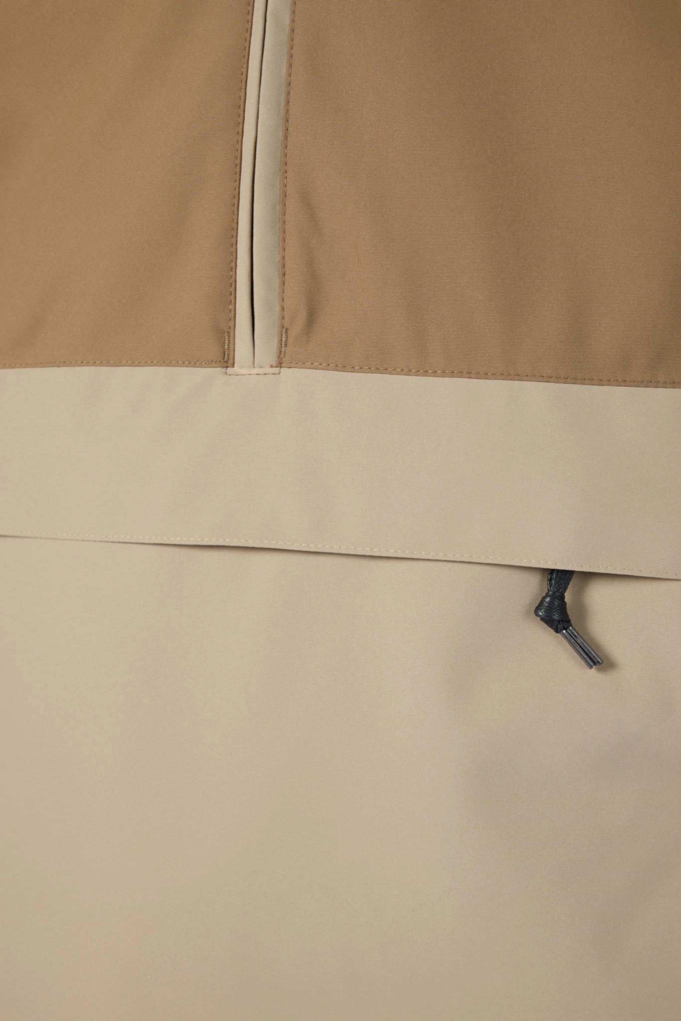 Close-up of a beige jacket with a zipper and button detail.